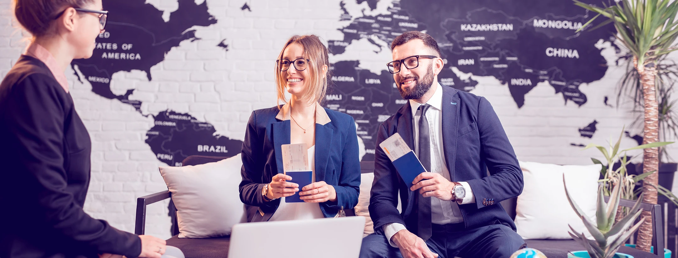 Three business professionals holding passports in a travel agency.