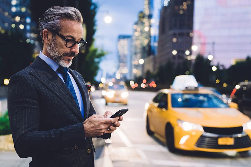 A mature man in a suit using smartphone on a city street at night.