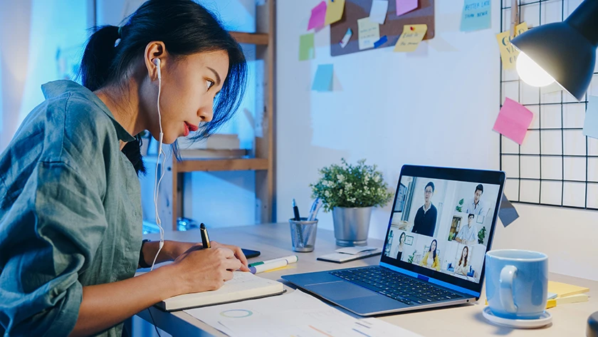 Woman attending virtual meeting on laptop in home office.