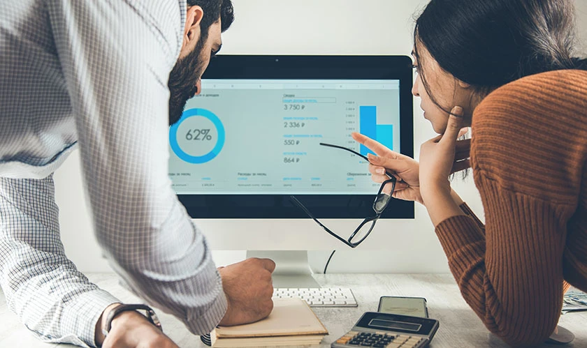 Two professionals analyzing data on a computer screen in an office.