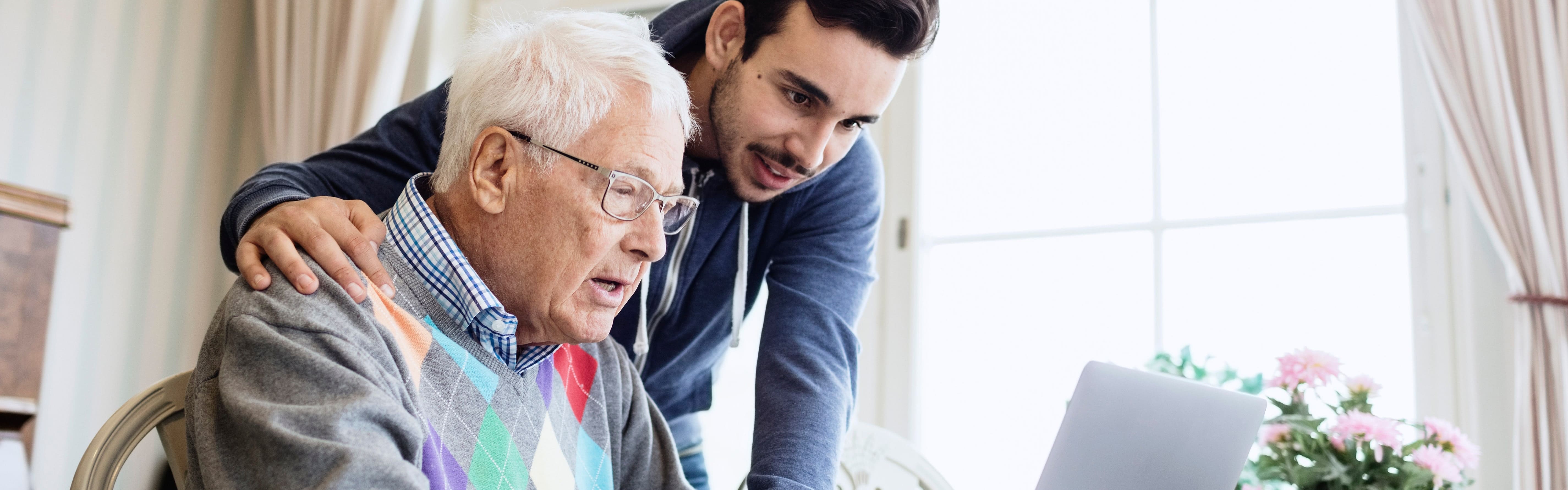 Joven ayudando al abuelo con la computadora