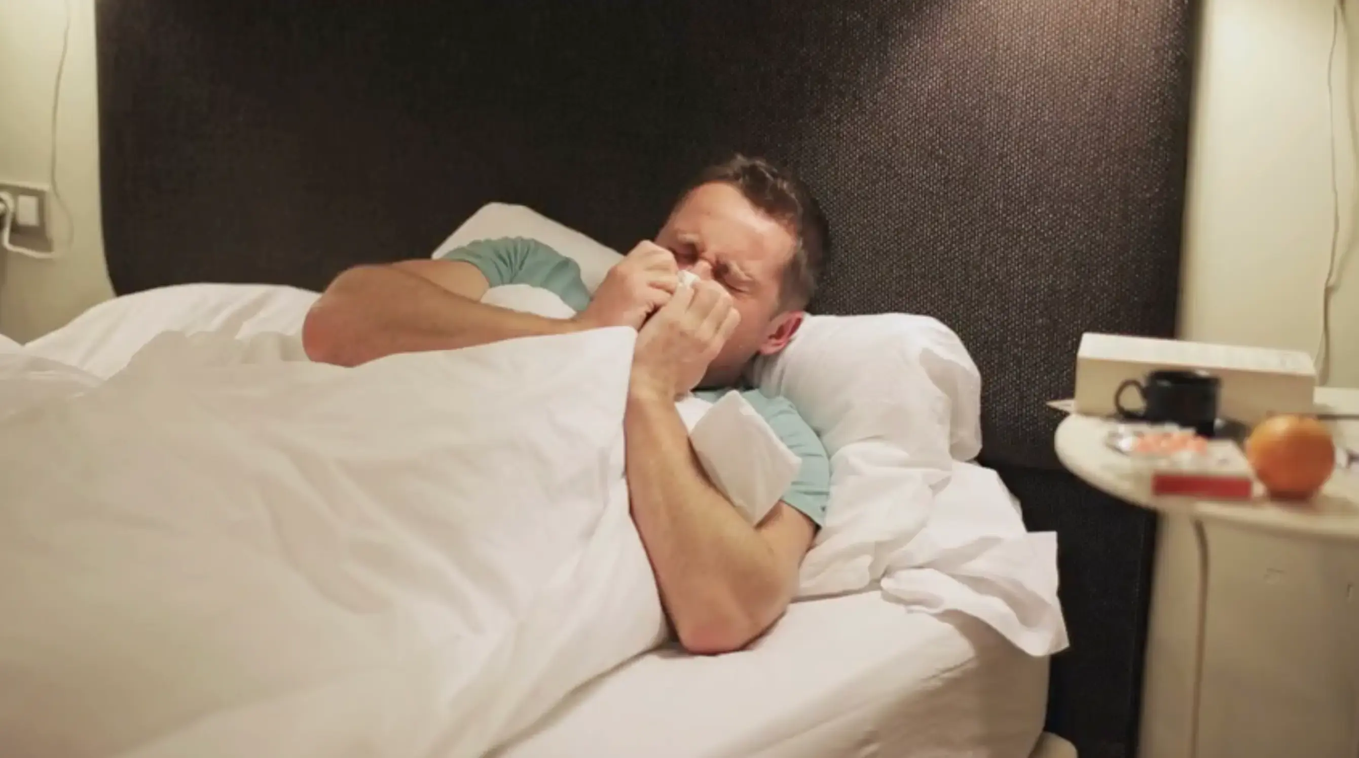 Man sneezing in bed