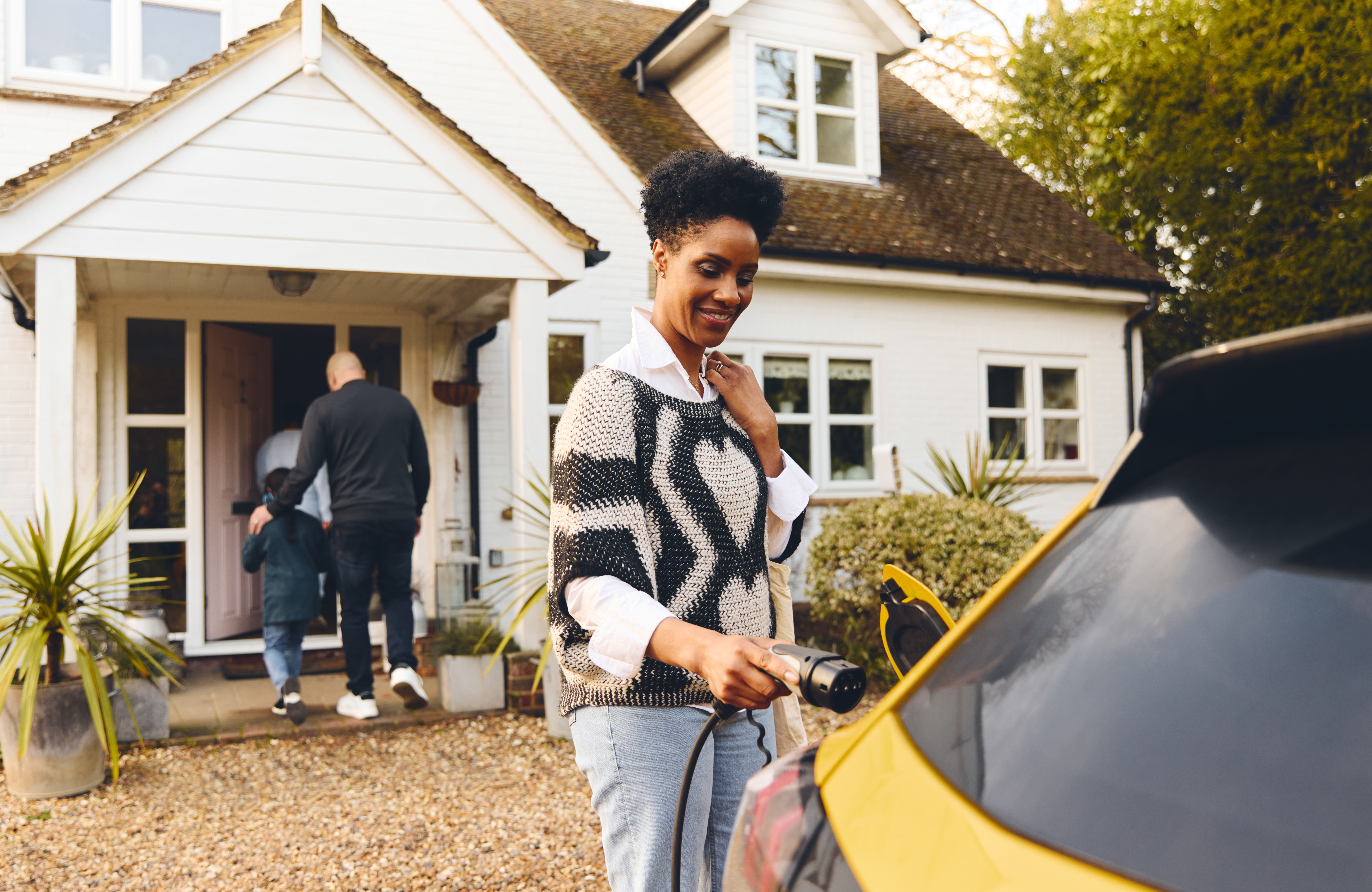 woman-plugging-in-electric-charger-into-car-with-f-2024-11-27-05-43-53-utc