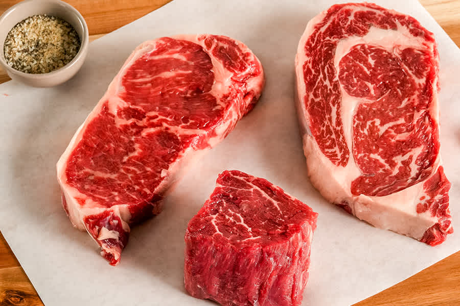 3 raw steaks on cutting board