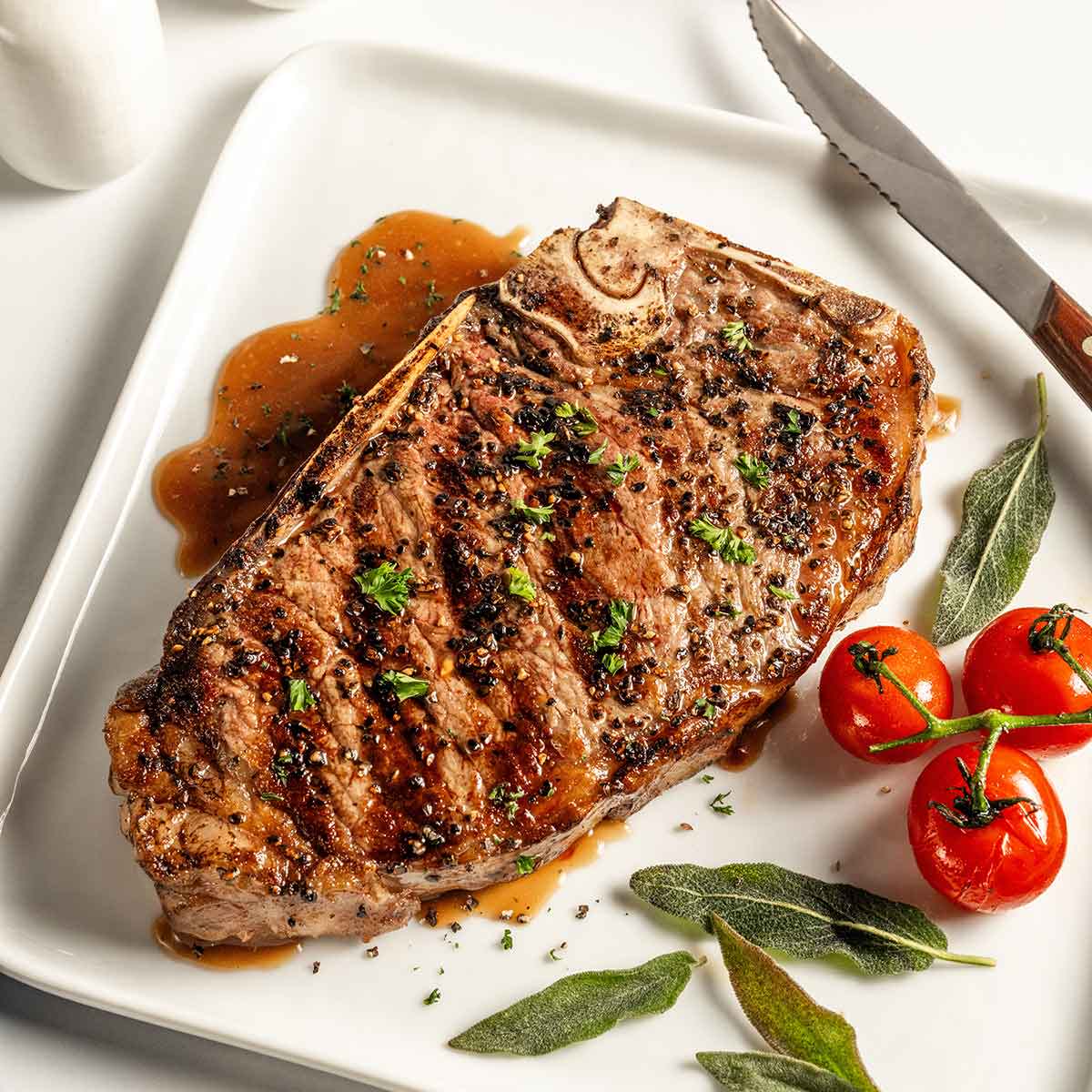 A juicy steak on a plate next to a glass of red wine.