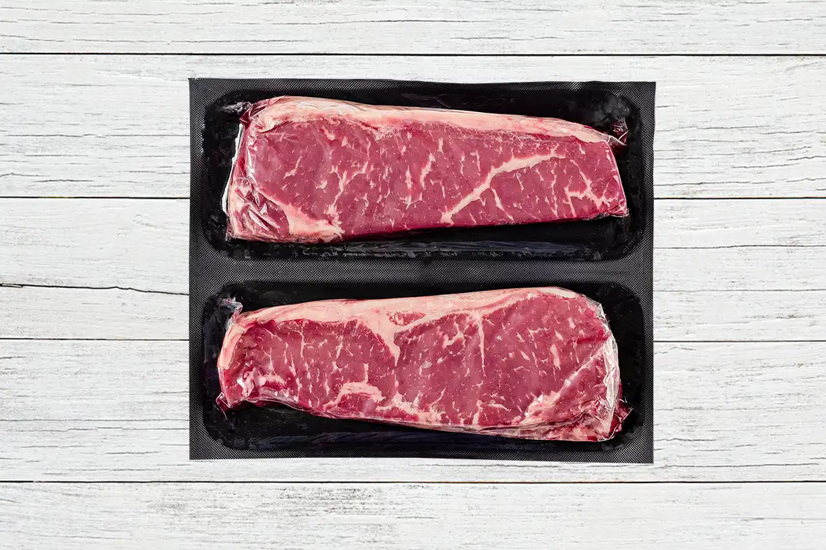 Packaged ny strips on wood background