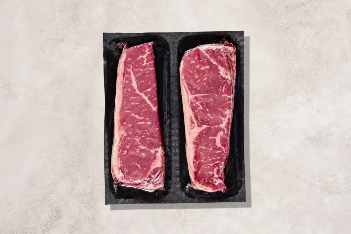 Packaged NY strips on a beige background