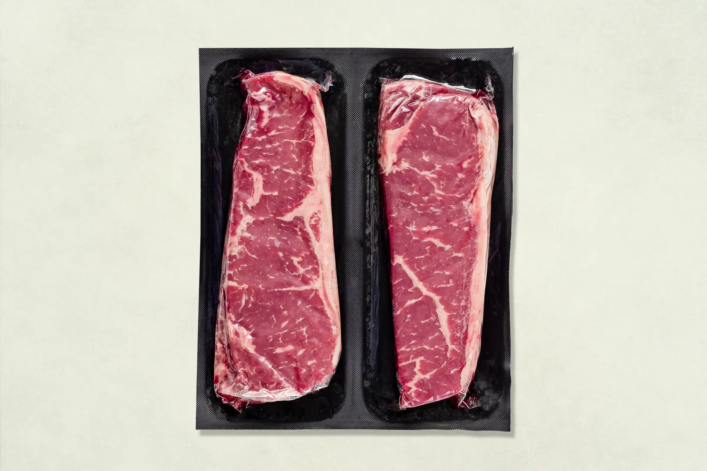 Packaged NY strips on a beige background