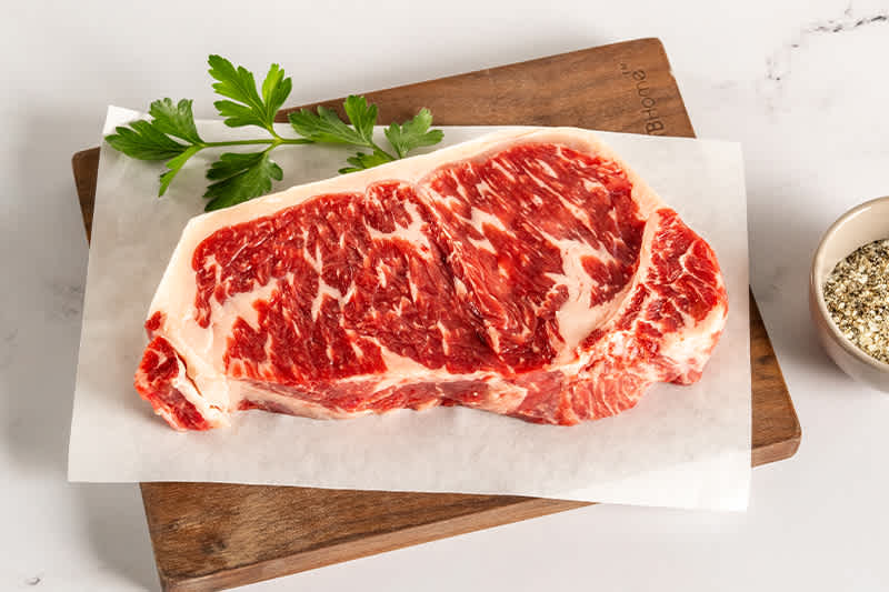 U.S. Pasture Raised NY Strip sitting on a wooden board.