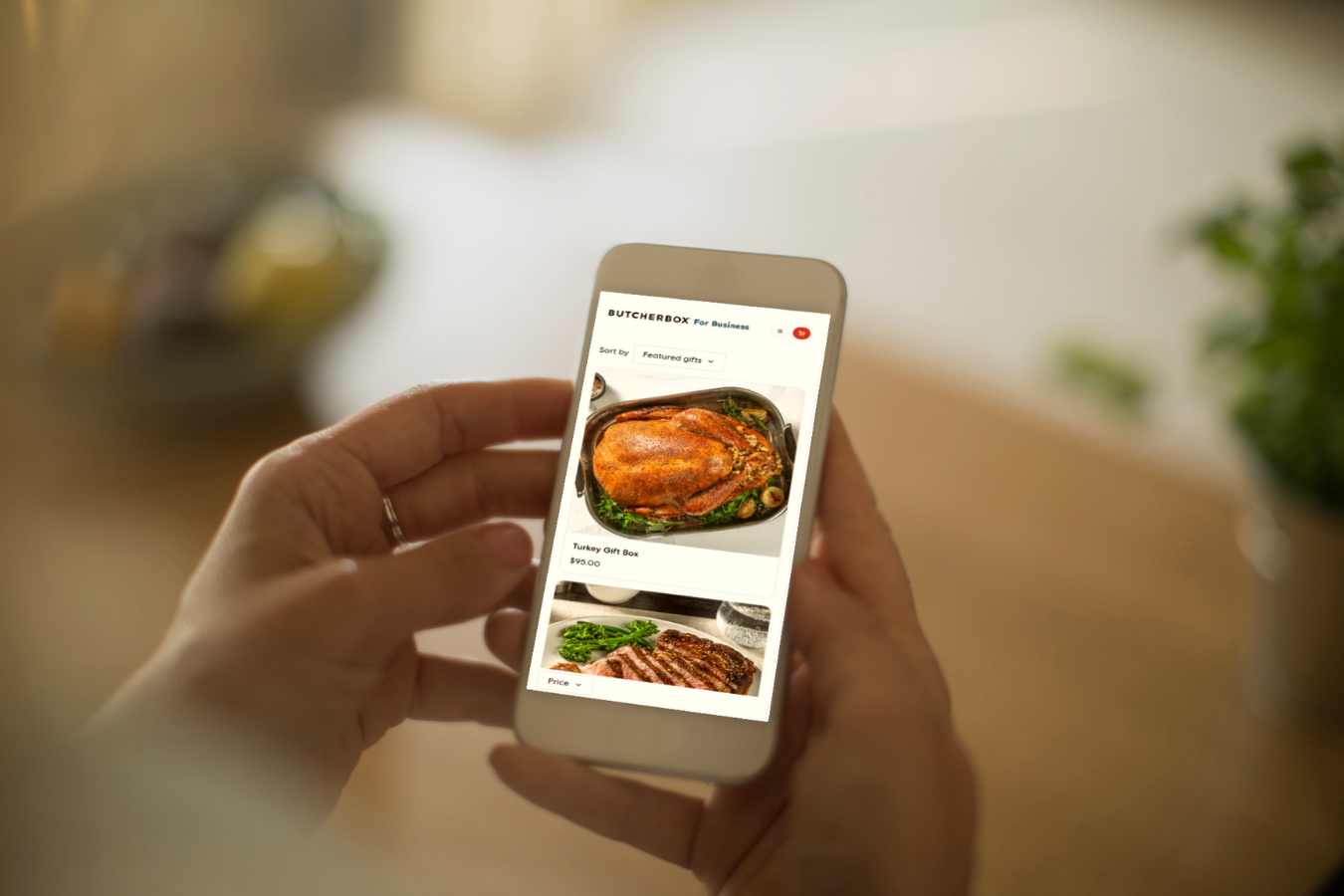 Hands holding a cell phone showing the order page for corporate gift boxes