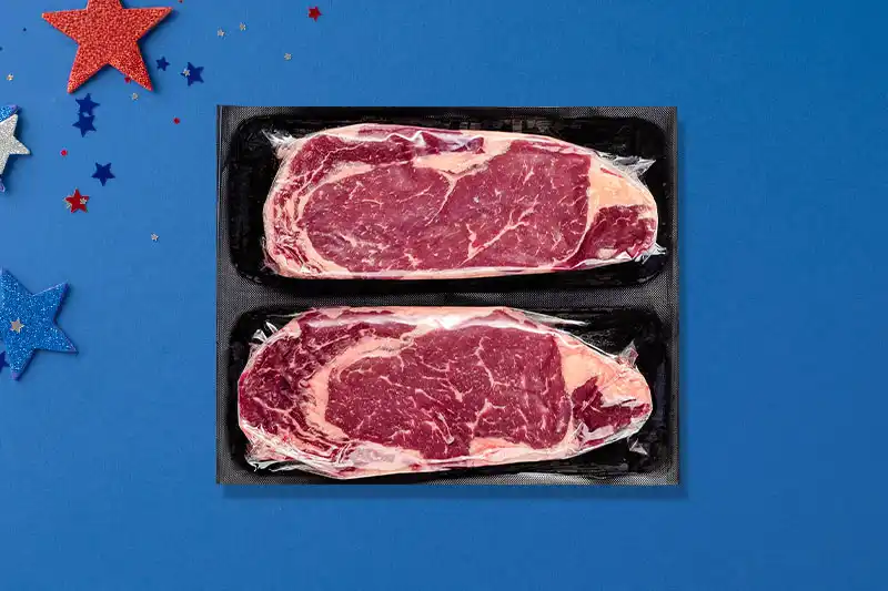 Packaged ribeyes on blue background