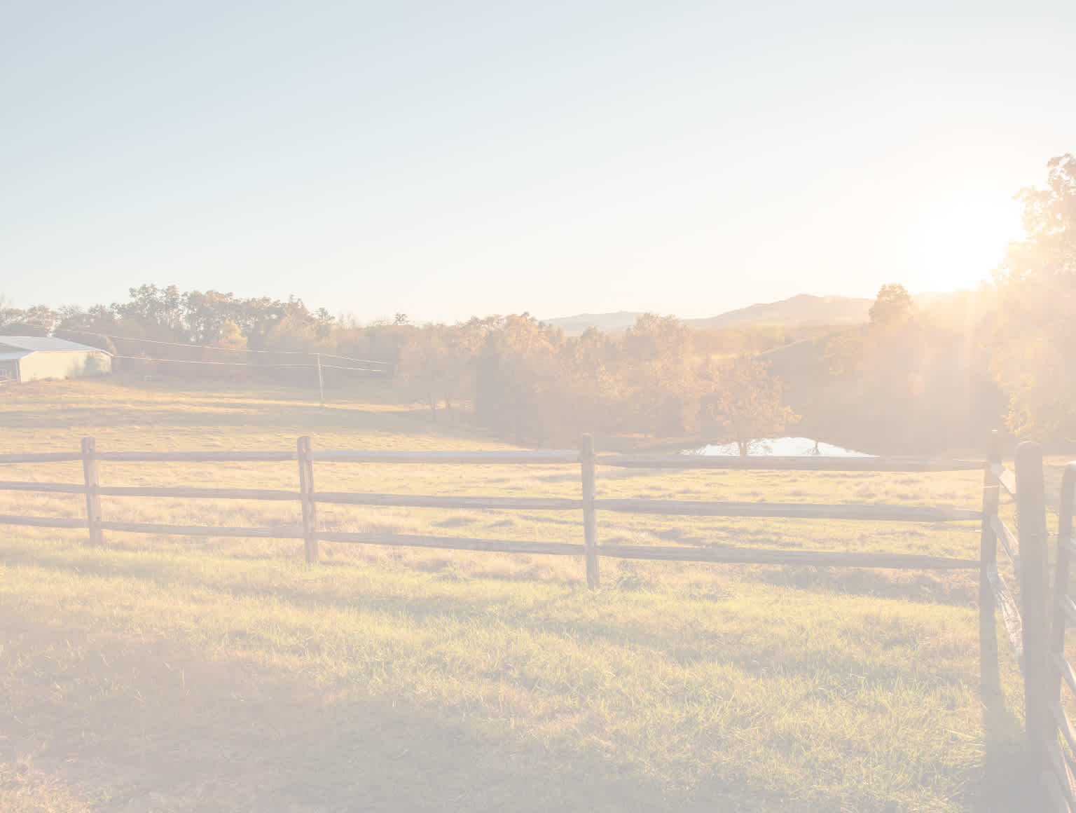 fence in a field at sunset