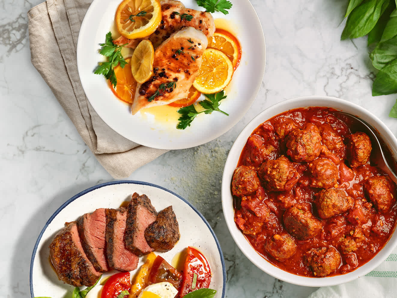 Plated chicken breasts, top sirloins, and meatballs
