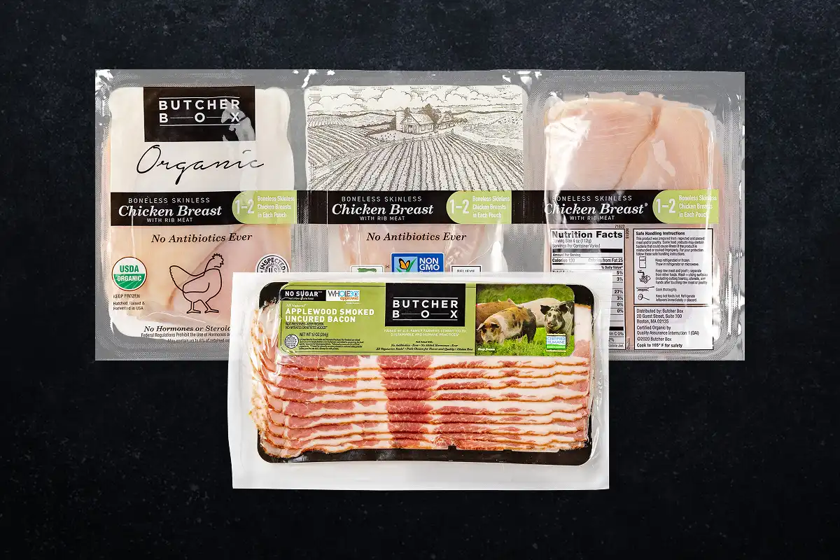 Packaged chicken breasts and bacon on a black background
