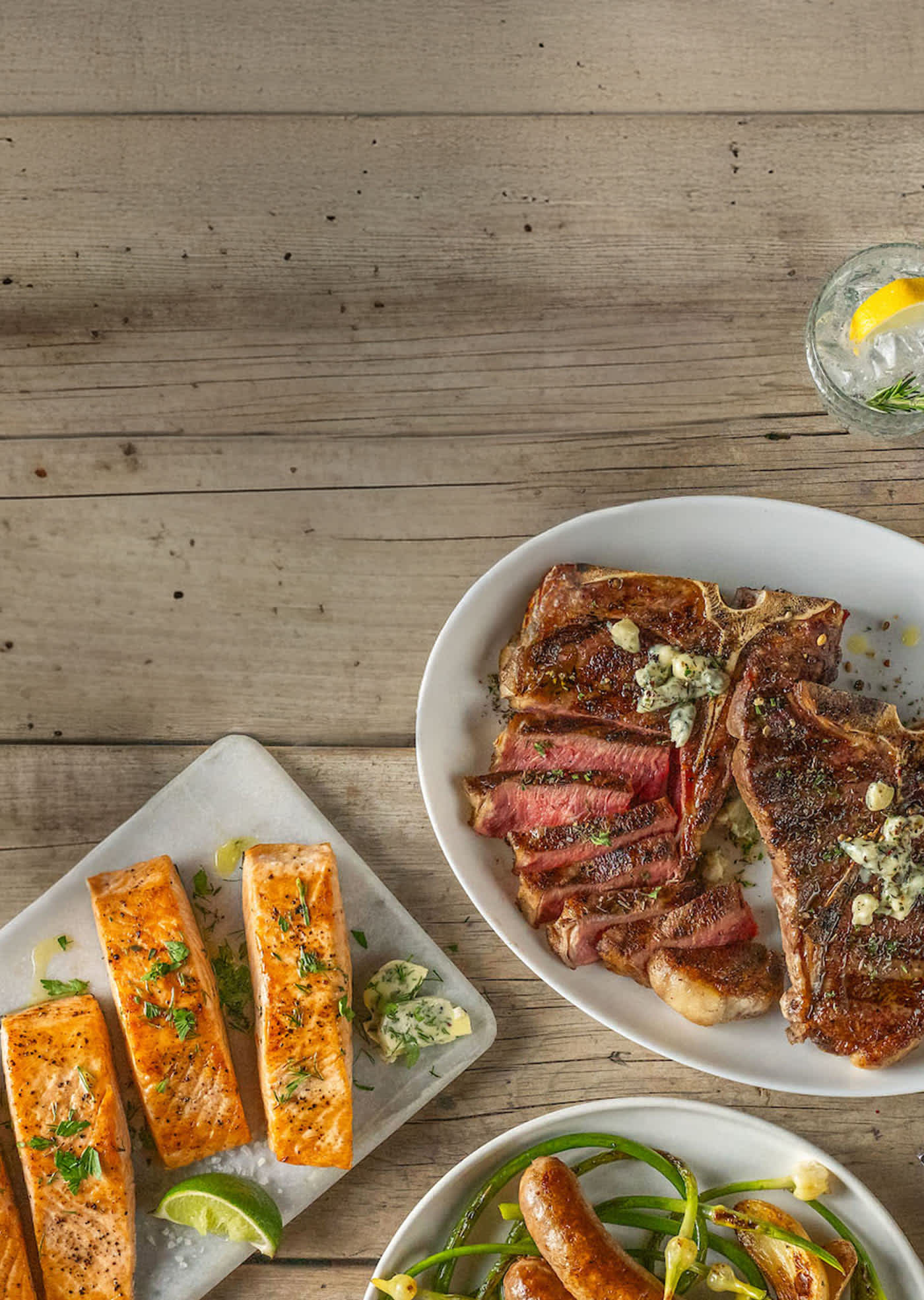 A table set with an assortment of dishes, including salmon, steak, vegetables, and various entrees, ready for a meal.