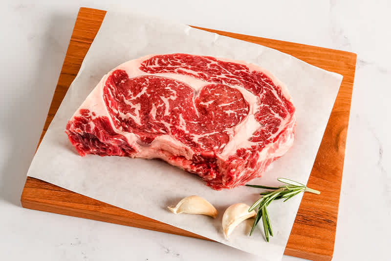 U.S. Pasture Raised Ribeye sitting on a wooden board.