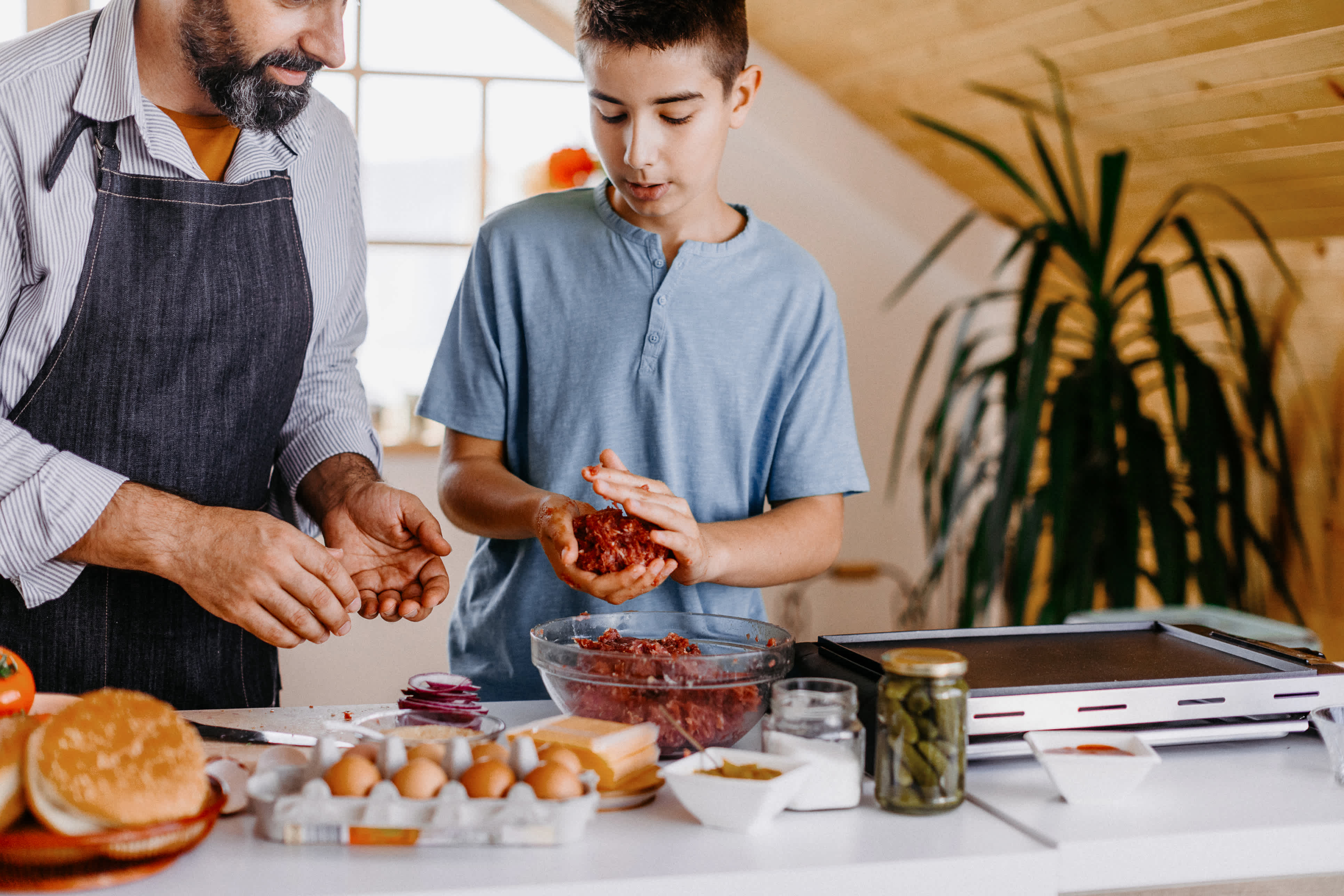 An adult and child make burgers together