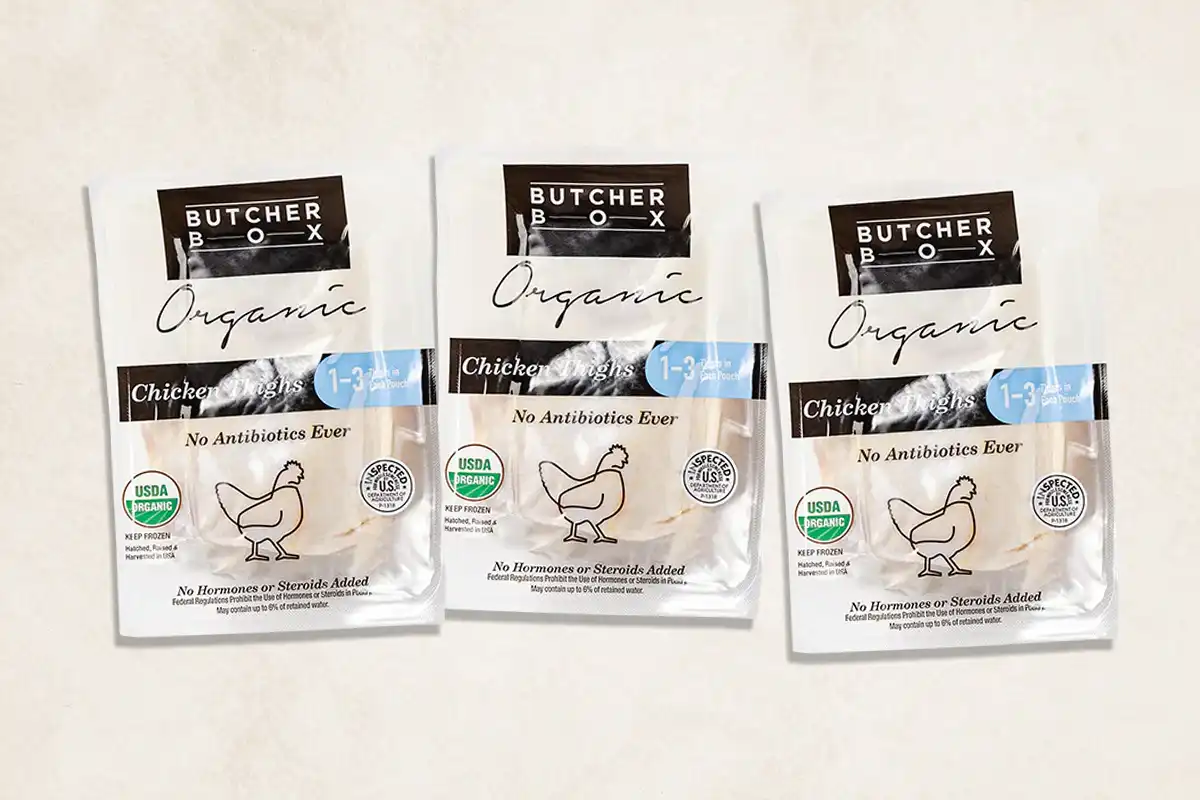Packaged chicken thighs on beige background