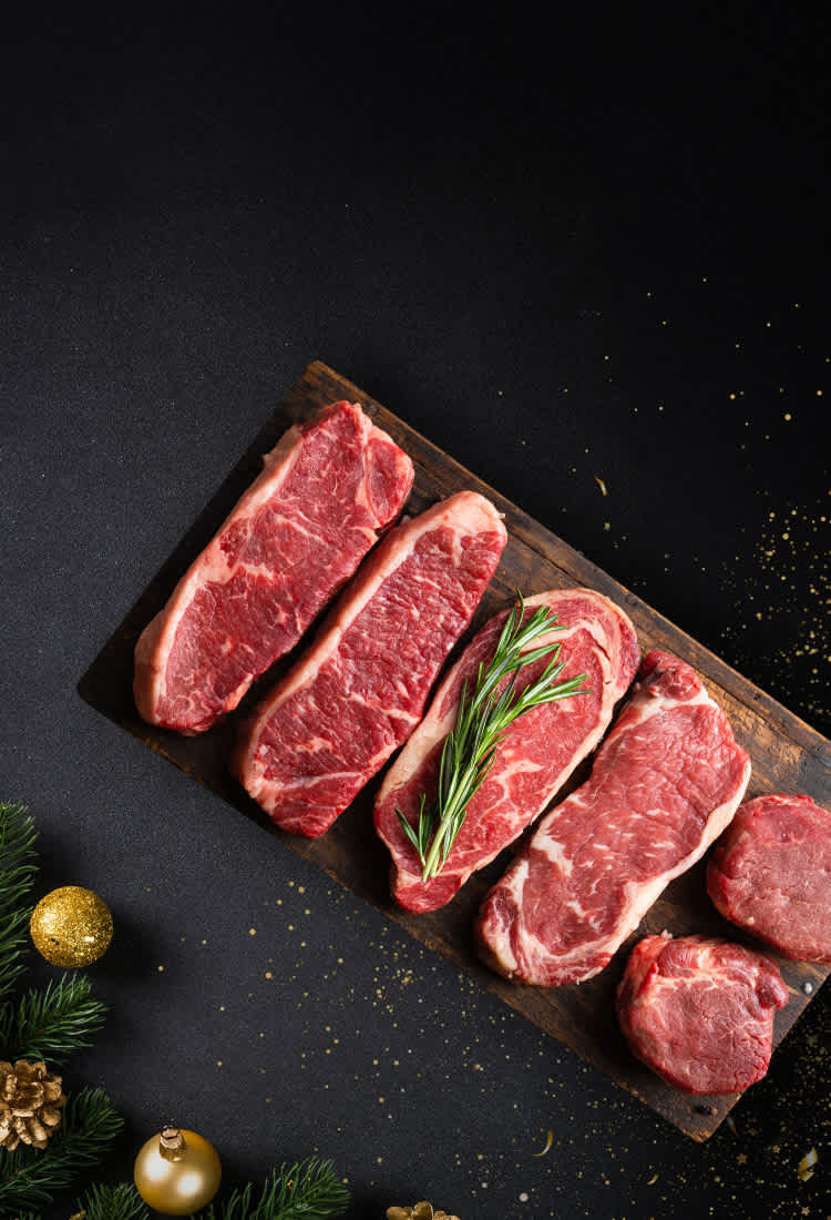Raw steaks on cutting board with black background