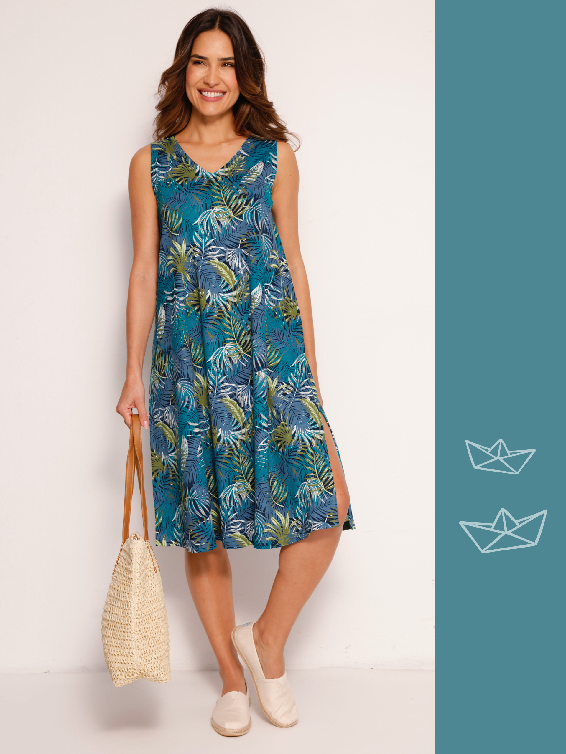 Ein Model trägt ein ärmelloses, knielanges Kleid mit blau-grünem Blattmuster und hält eine geflochtene Tasche.