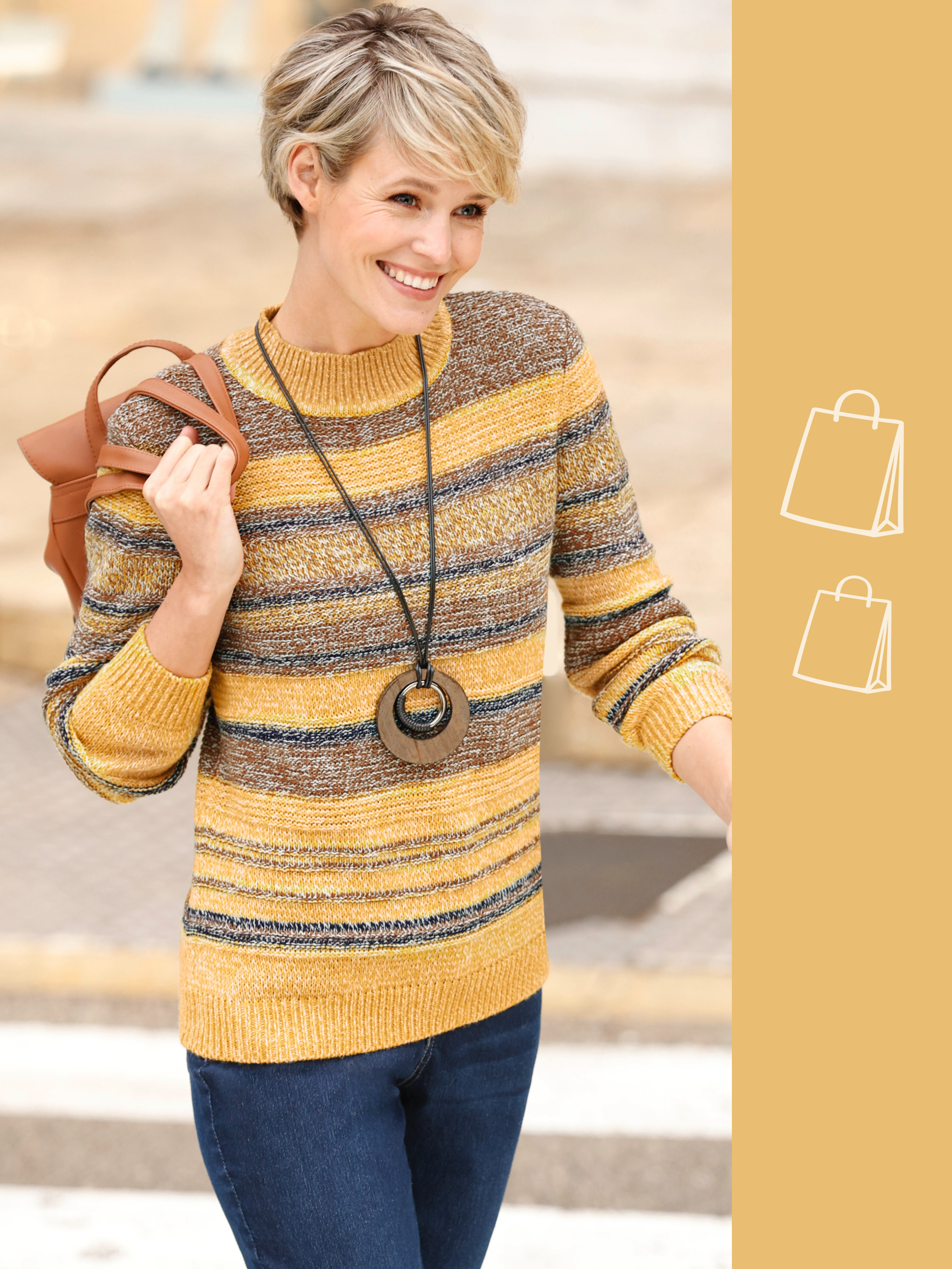 Model má na sebe pruhovaný sveter v žltých, hnedých a modrých tónoch s modrými džínami a hnedou taškou.