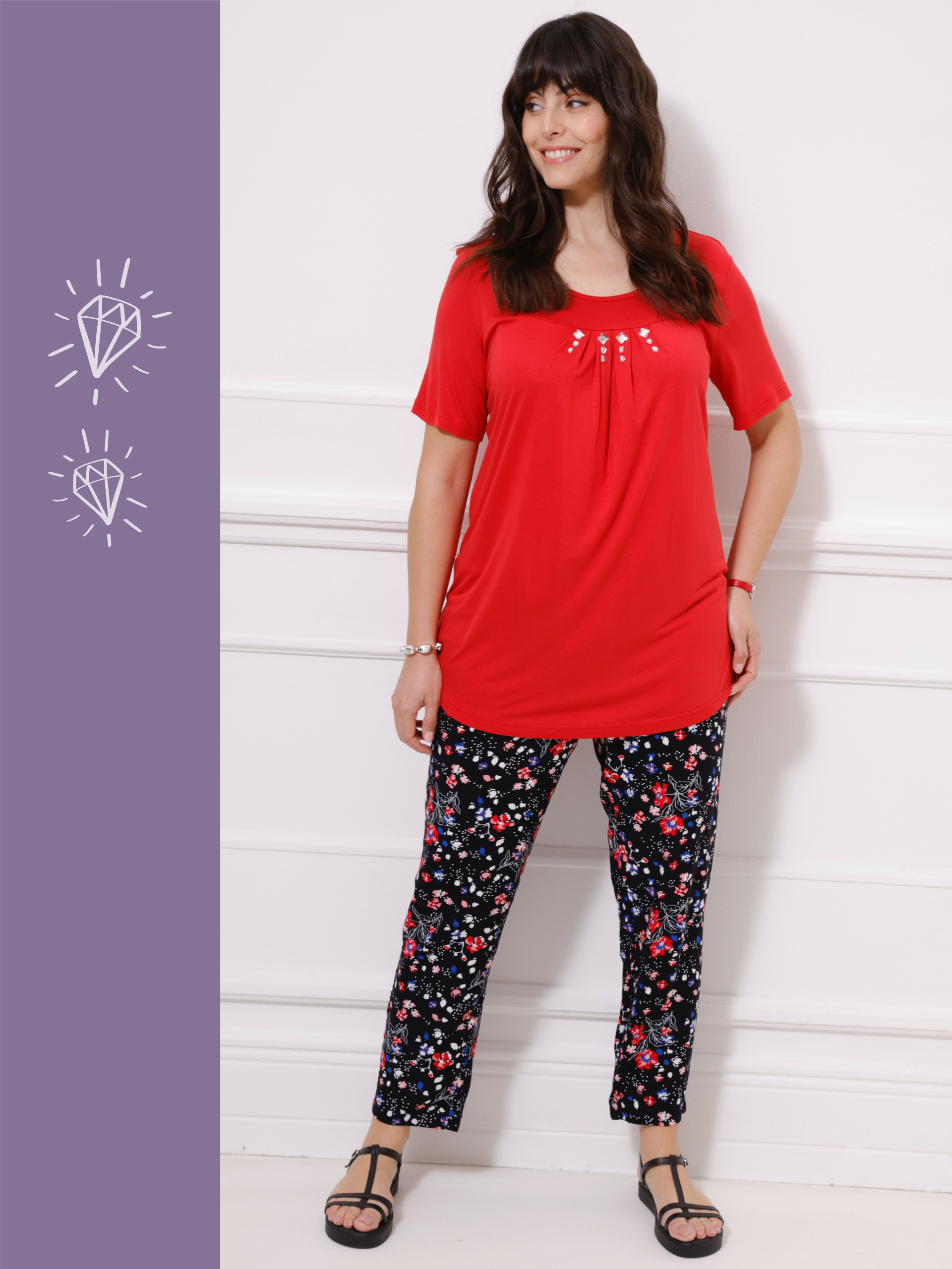 Ein Model trägt ein rotes T-Shirt und schwarze Blumenleggings, während es vor einer weißen Wand steht.