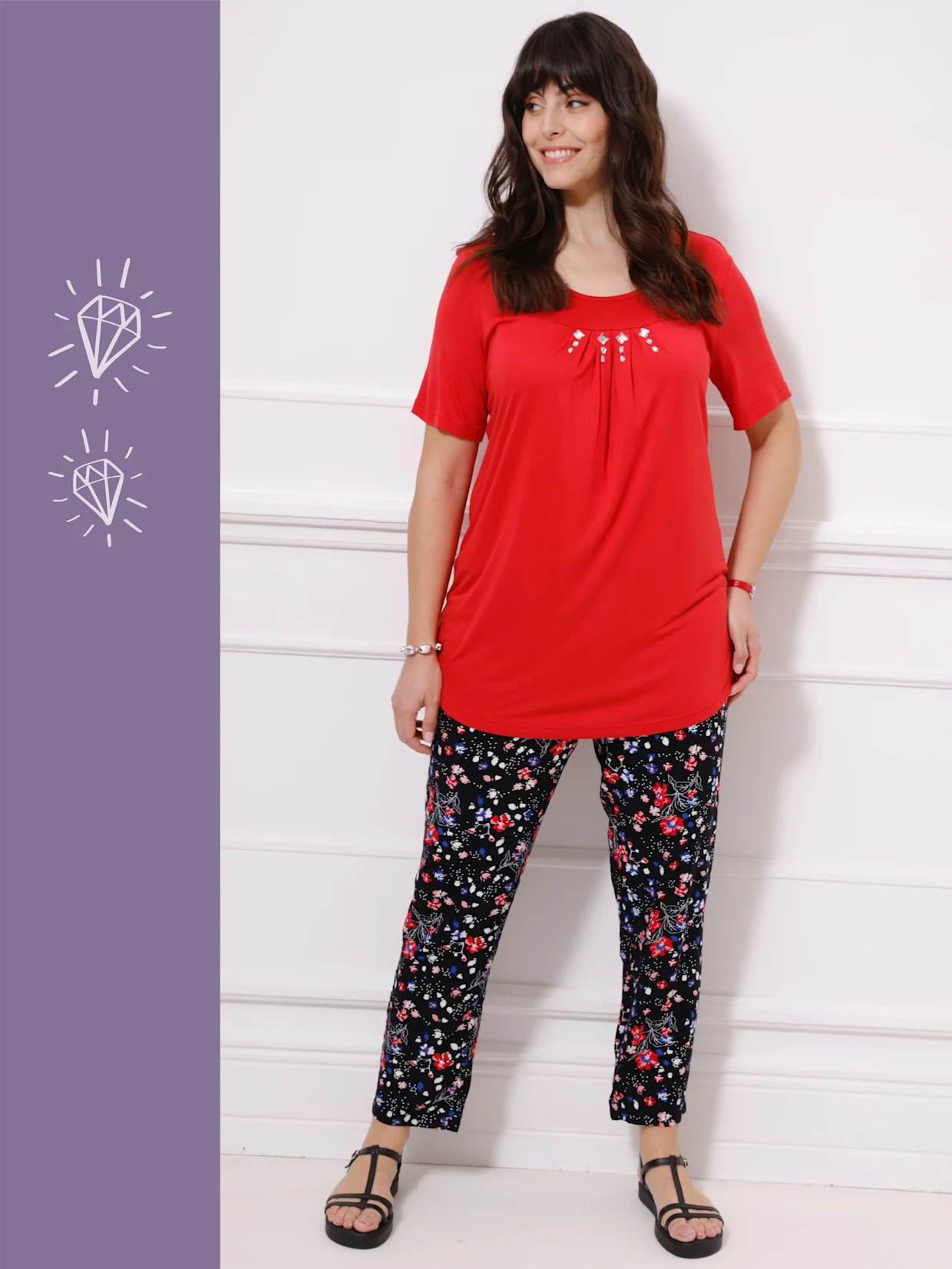 Ein Model trägt ein rotes T-Shirt und schwarze Blumenleggings, während es vor einer weißen Wand steht.