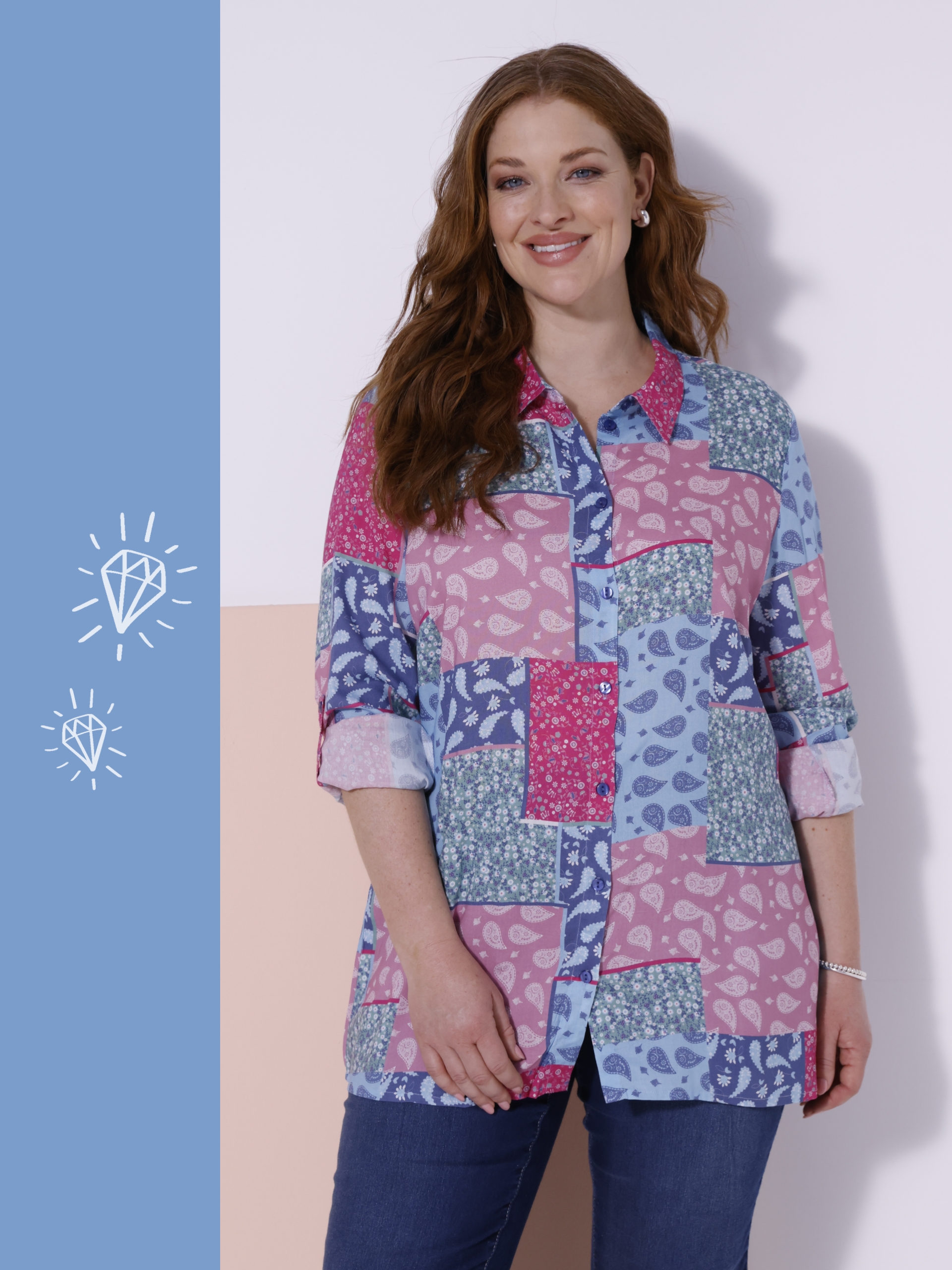 Ein Model steht vor einer zweifarbigen Wand, trägt eine langärmelige Bluse mit Patchwork-Muster in Blau- und Rosatönen und blaue Jeans.