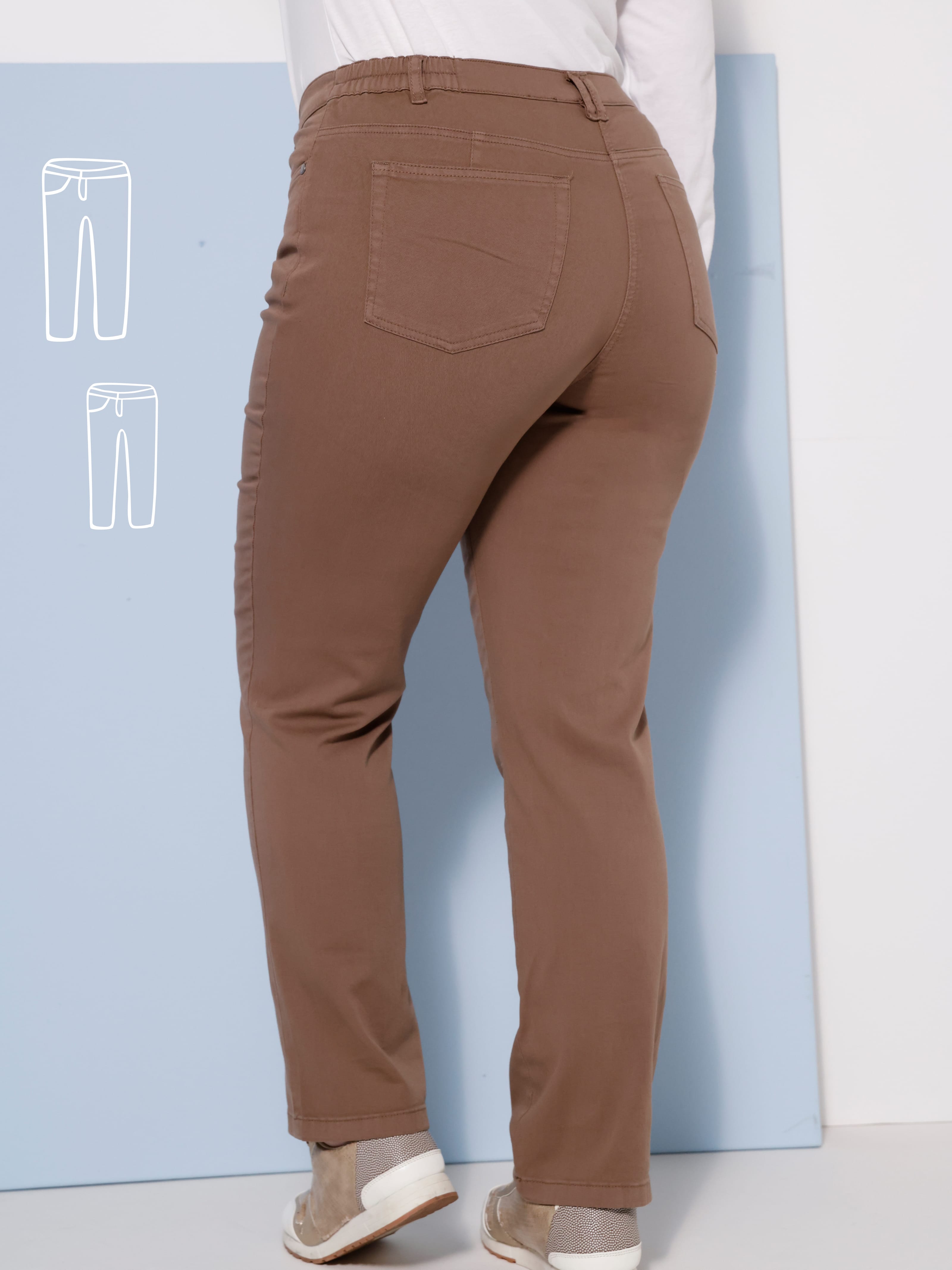 Ein Model von hinten in brauner Hose und weißen Schuhen.