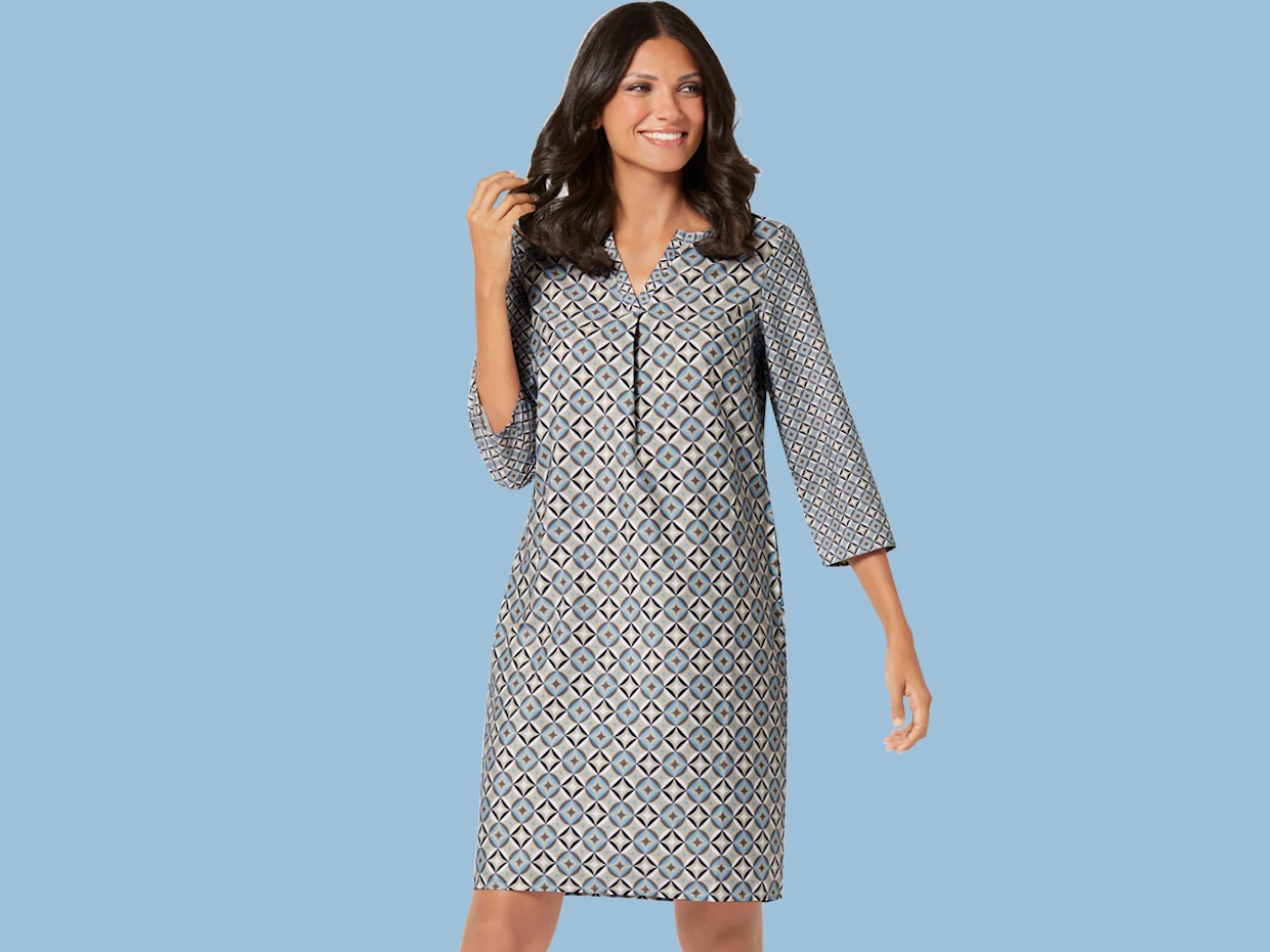 Damenkleid mit geometrischem Muster, dreiviertel langen Ärmeln und V-Ausschnitt vor hellblauem Hintergrund.