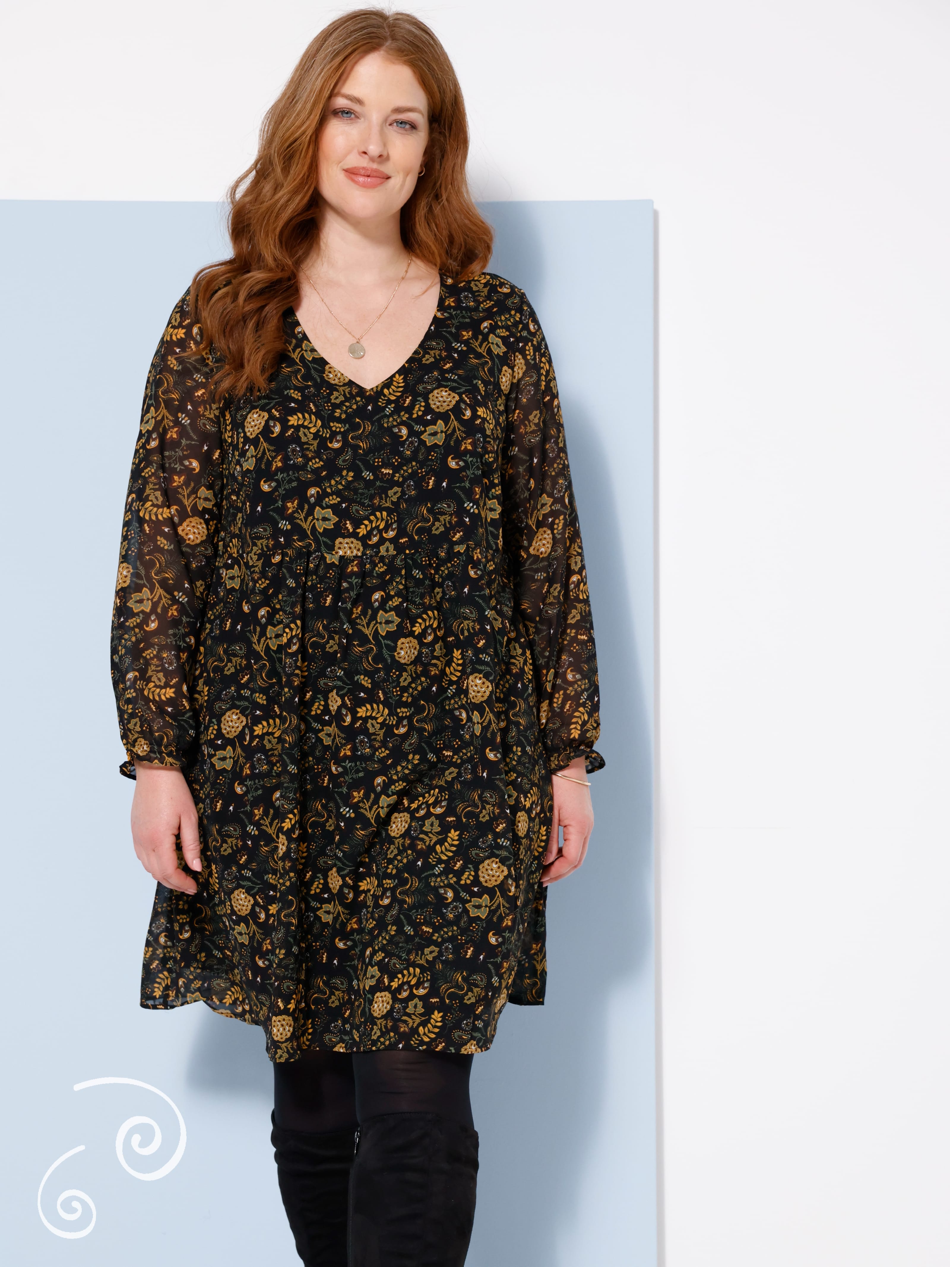 Ein Model trägt ein schwarzes Kleid mit floralem Muster.