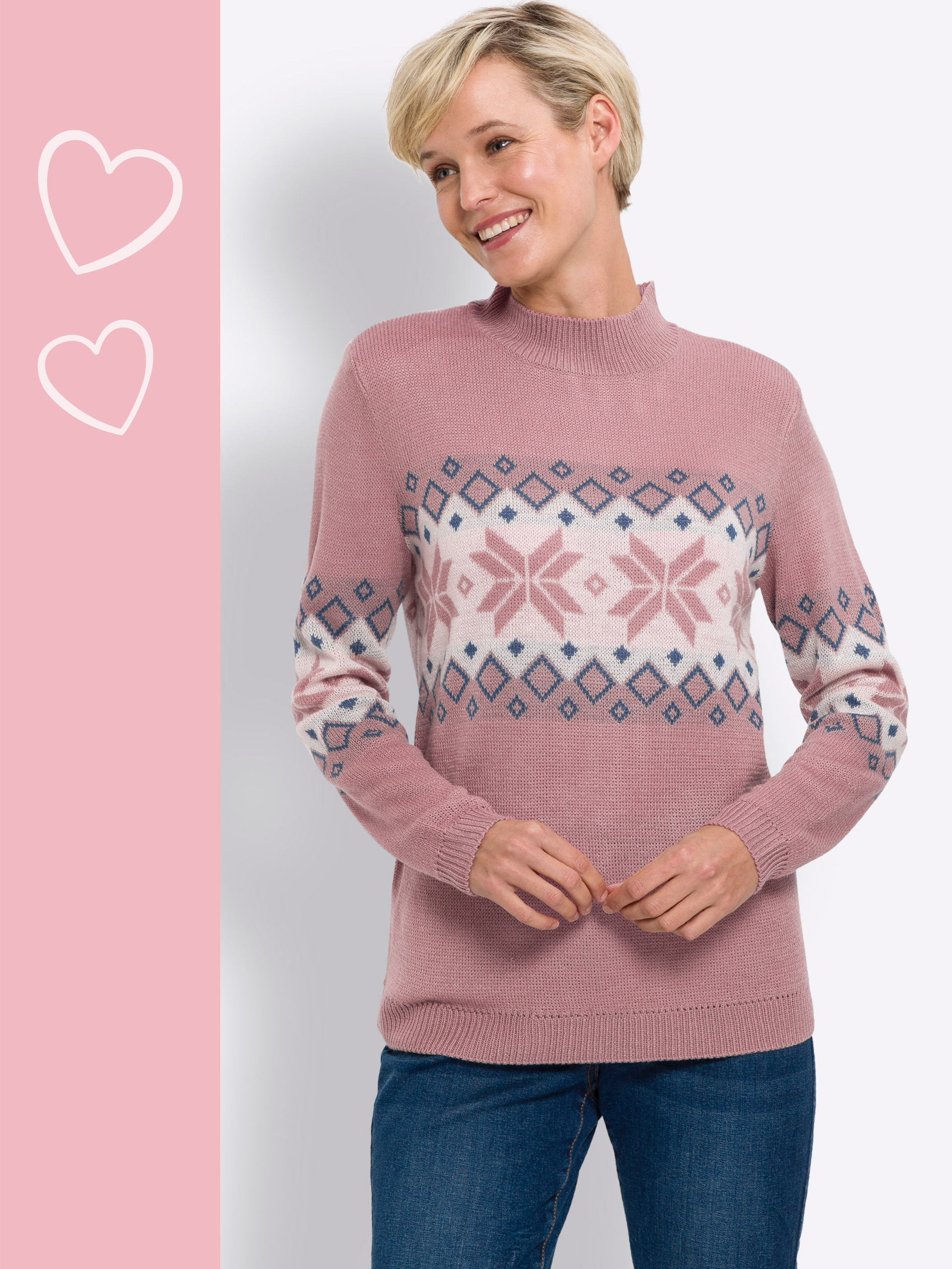 Model má na sebe ružový sveter s nórskym vzorom v bielej a modrej farbe, v kombinácii s modrými džínsami.