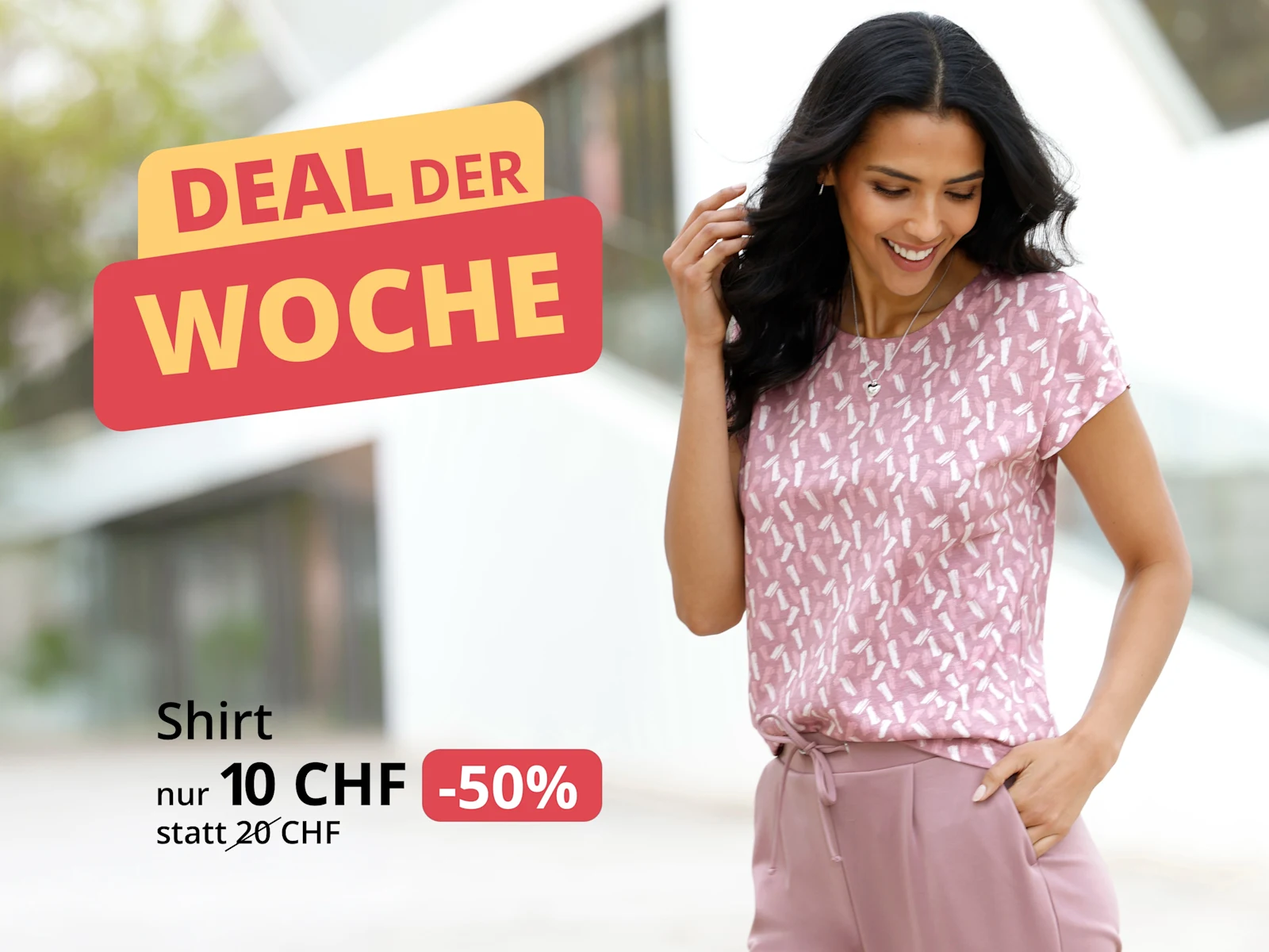 Ein Model trägt ein rosa gemustertes Kurzarmshirt und eine rosa Hose. Text: 'DEAL DER WOCHE', 'Shirt nur 10 CHF statt 20 CHF und '-50%'.