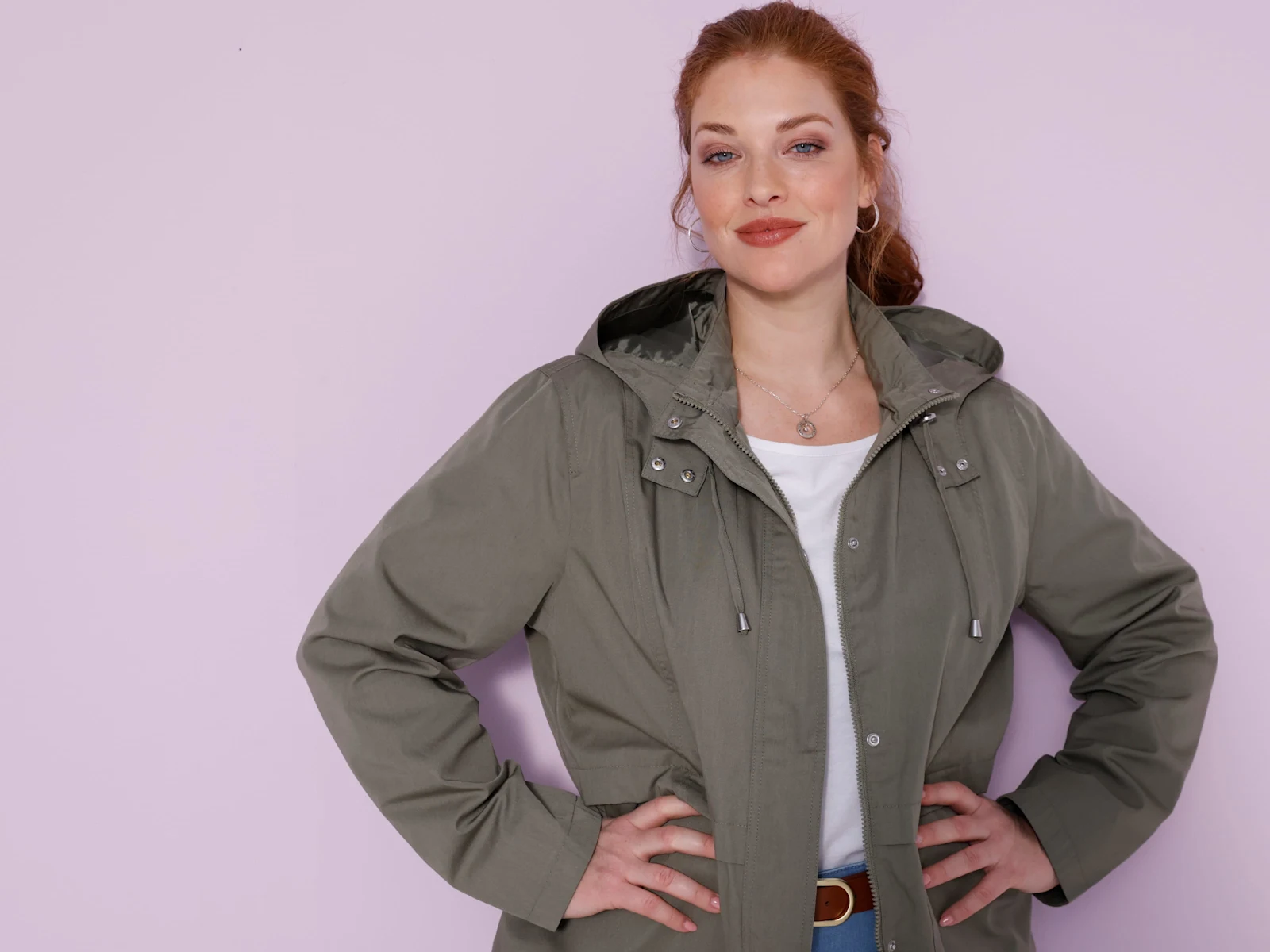 Model má oblečenú olivovozelenú bundu s kapucňou.