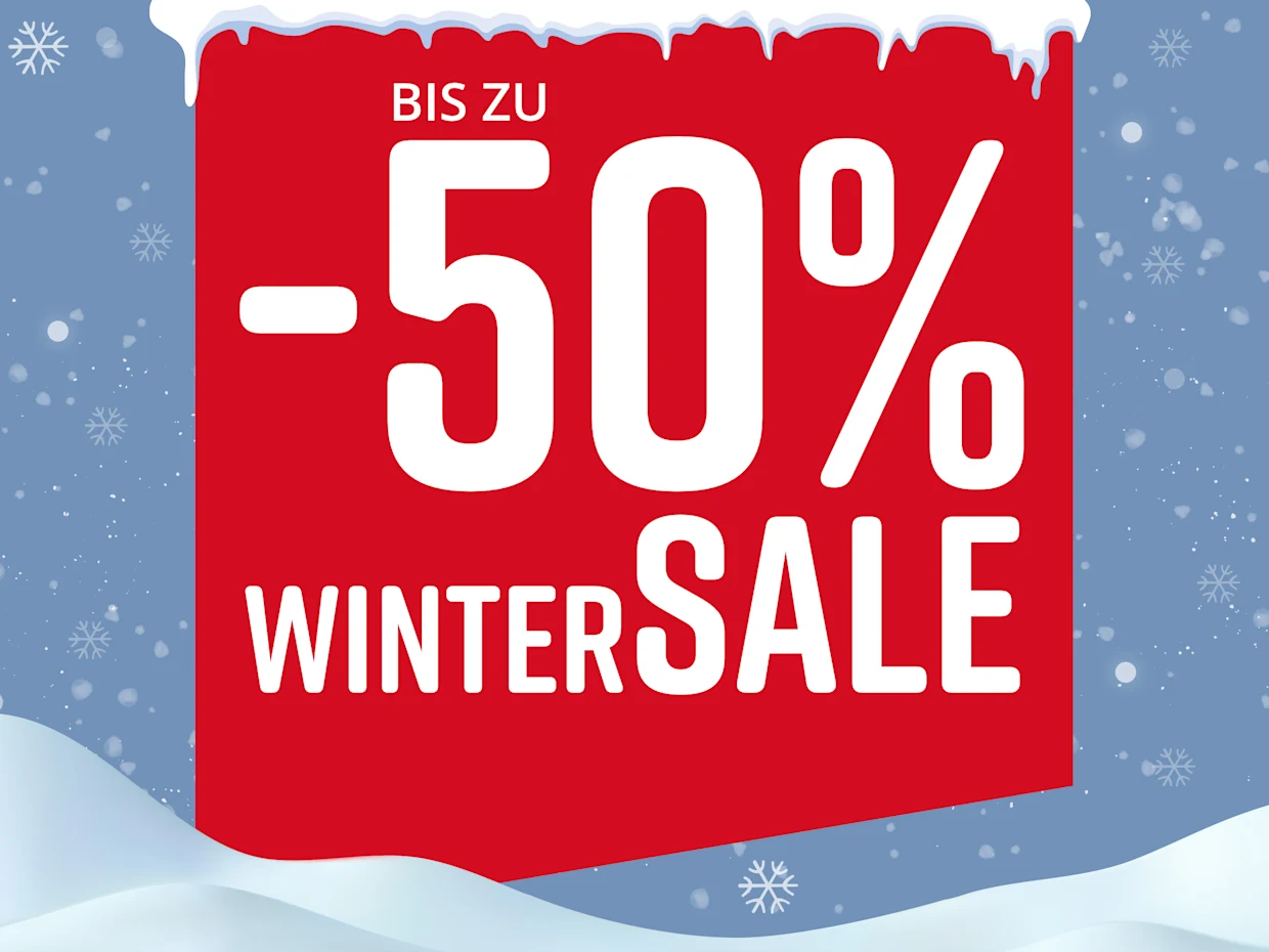 Rotes Schild mit Text 'Bis zu -50% Wintersale' vor winterlicher Schneelandschaft mit Schneeflocken.