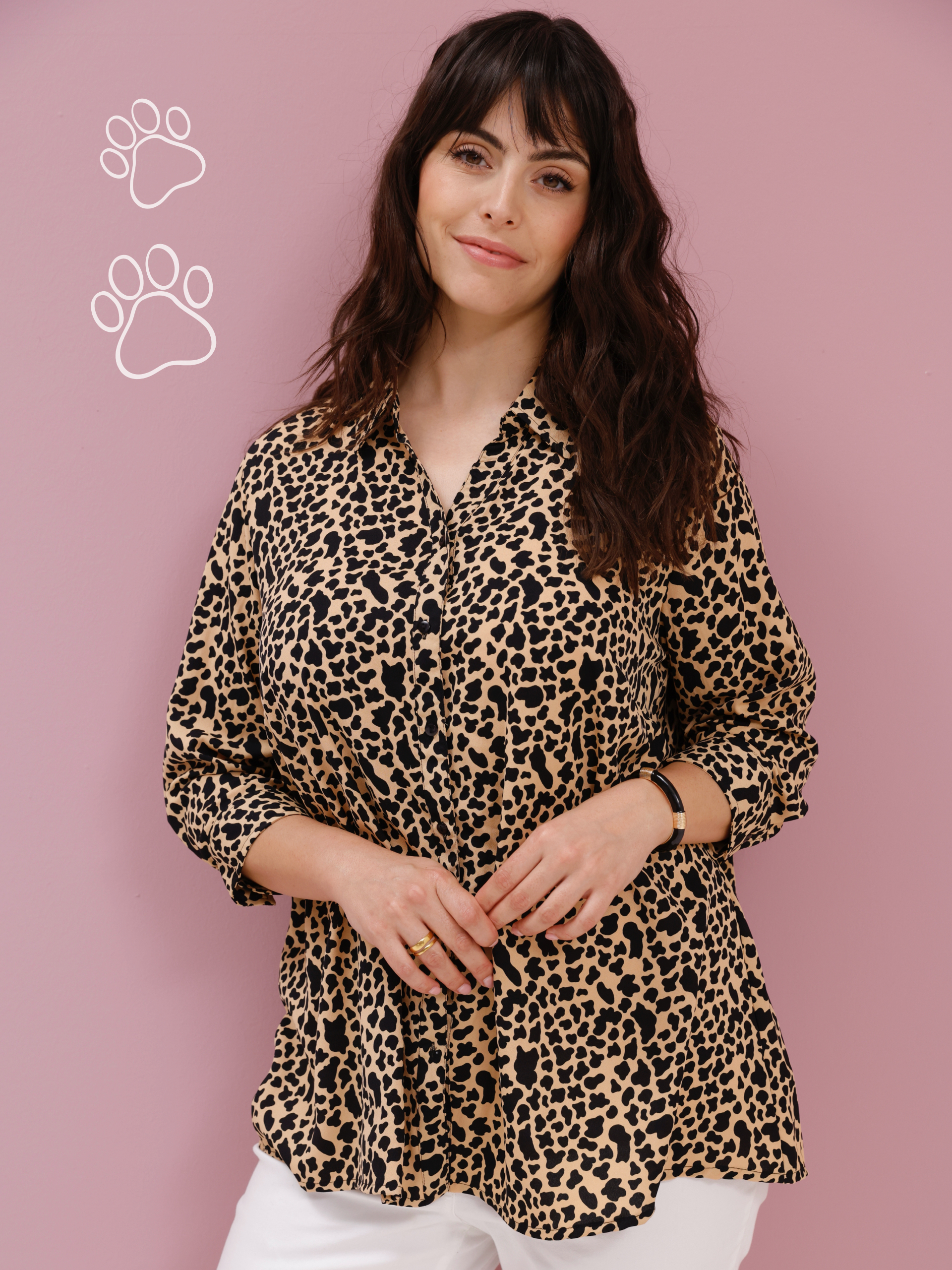 Ein Model präsentiert eine langärmlige Bluse mit Leopardenmuster vor einem rosa Hintergrund.