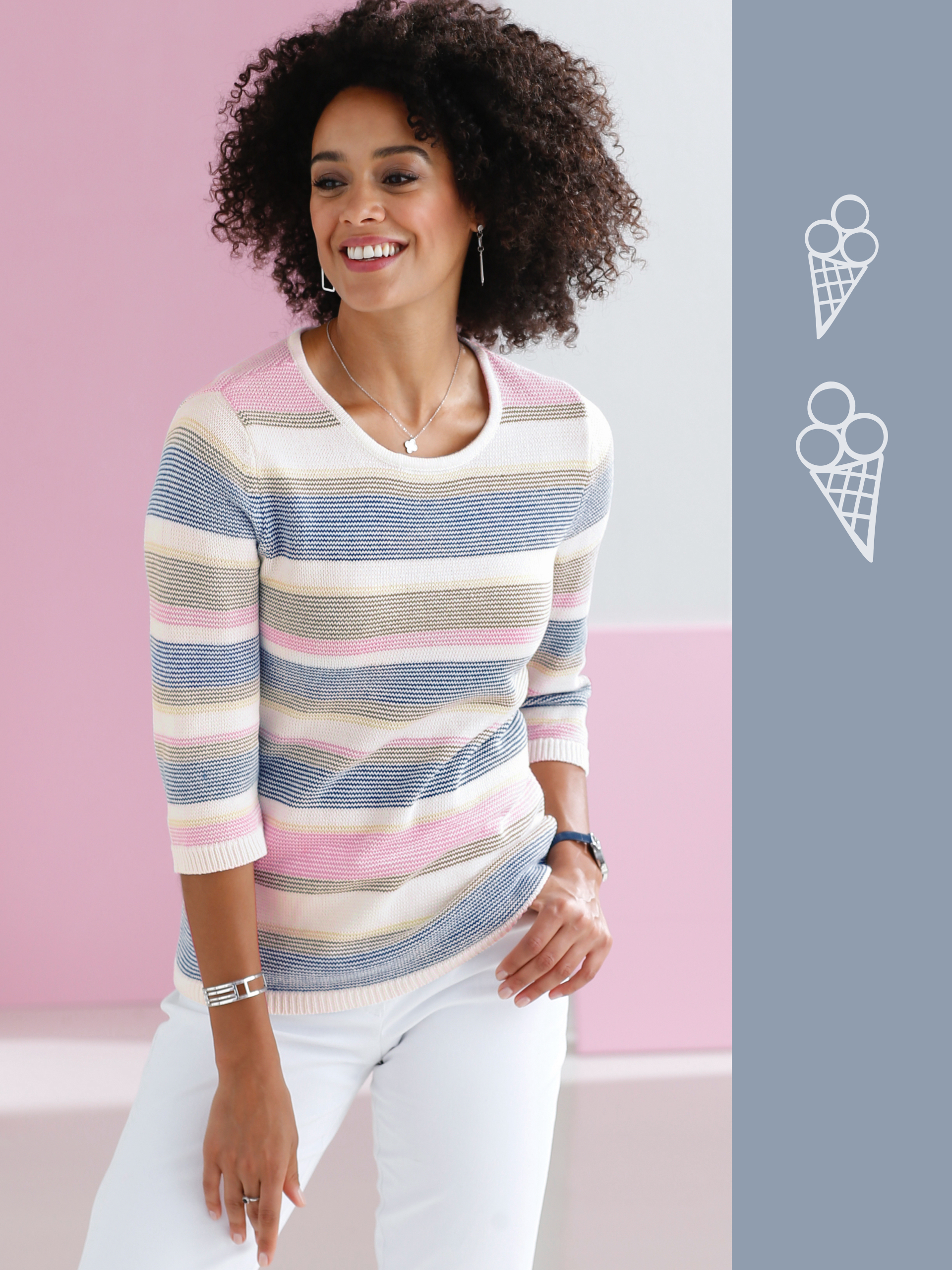 Model má na sebe pruhovaný sveter v pastelových farbách s tromištvrťovými rukávmi a biele nohavice.
