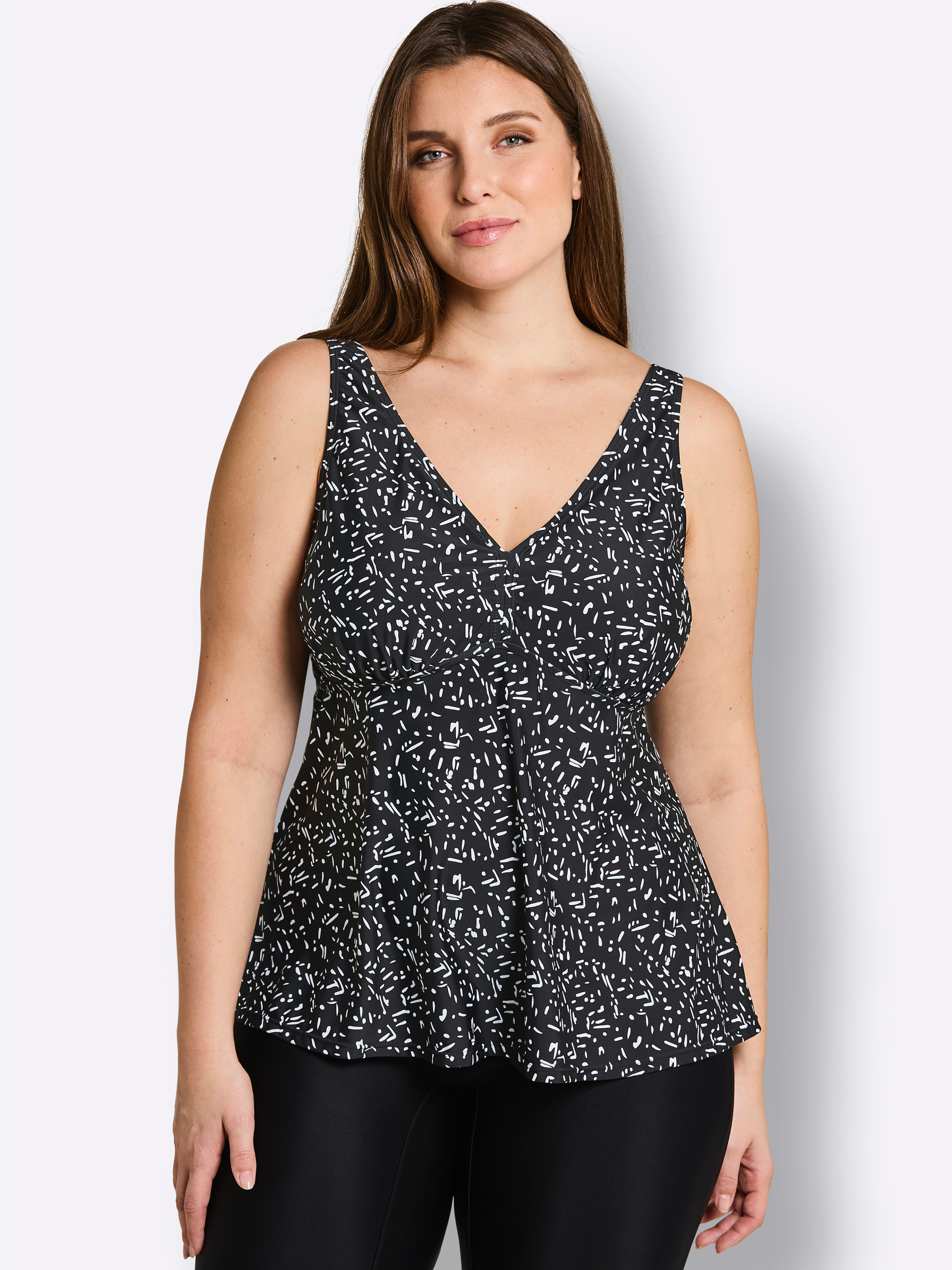 Ein Model trägt einen schwarz-weiß gemusterten Tankini vor weißem Hintergrund.