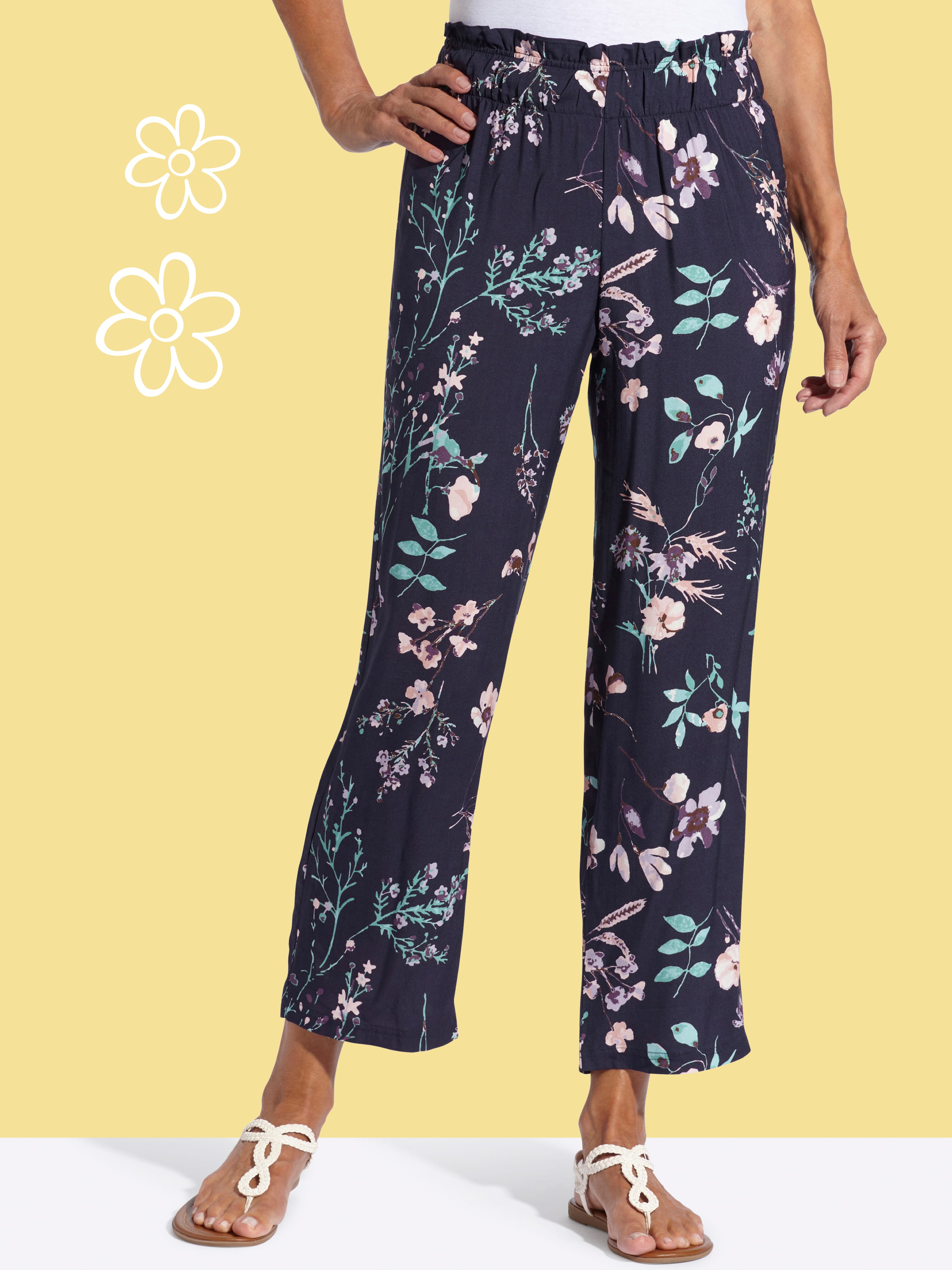 En modell bär mörkblå byxor med blommönster, löst sittande och med elastisk midja.