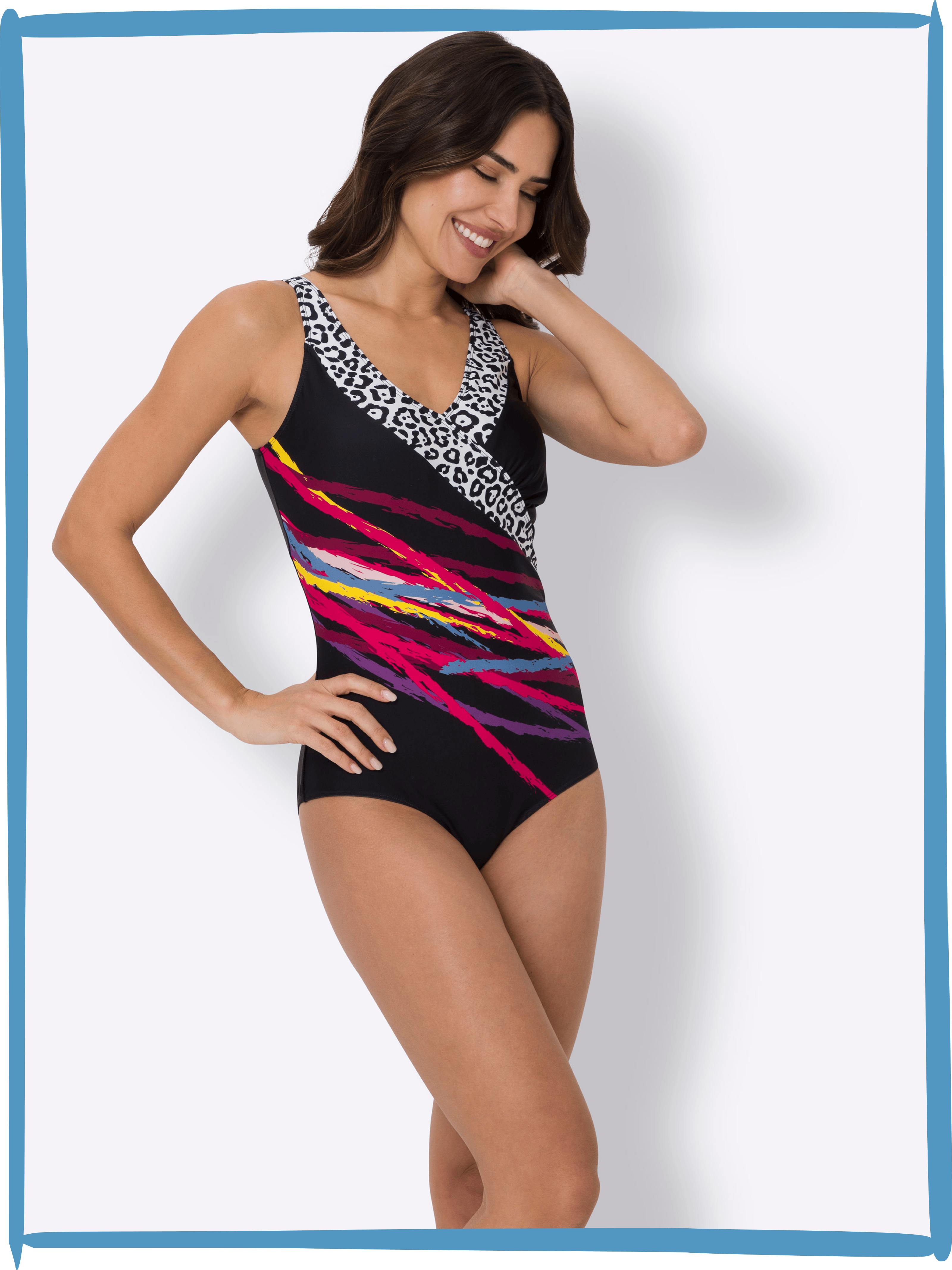 Ein Model trägt einen schwarz-bunten Badeanzug mit weißem Muster am Ausschnitt, steht vor weißem Hintergrund.