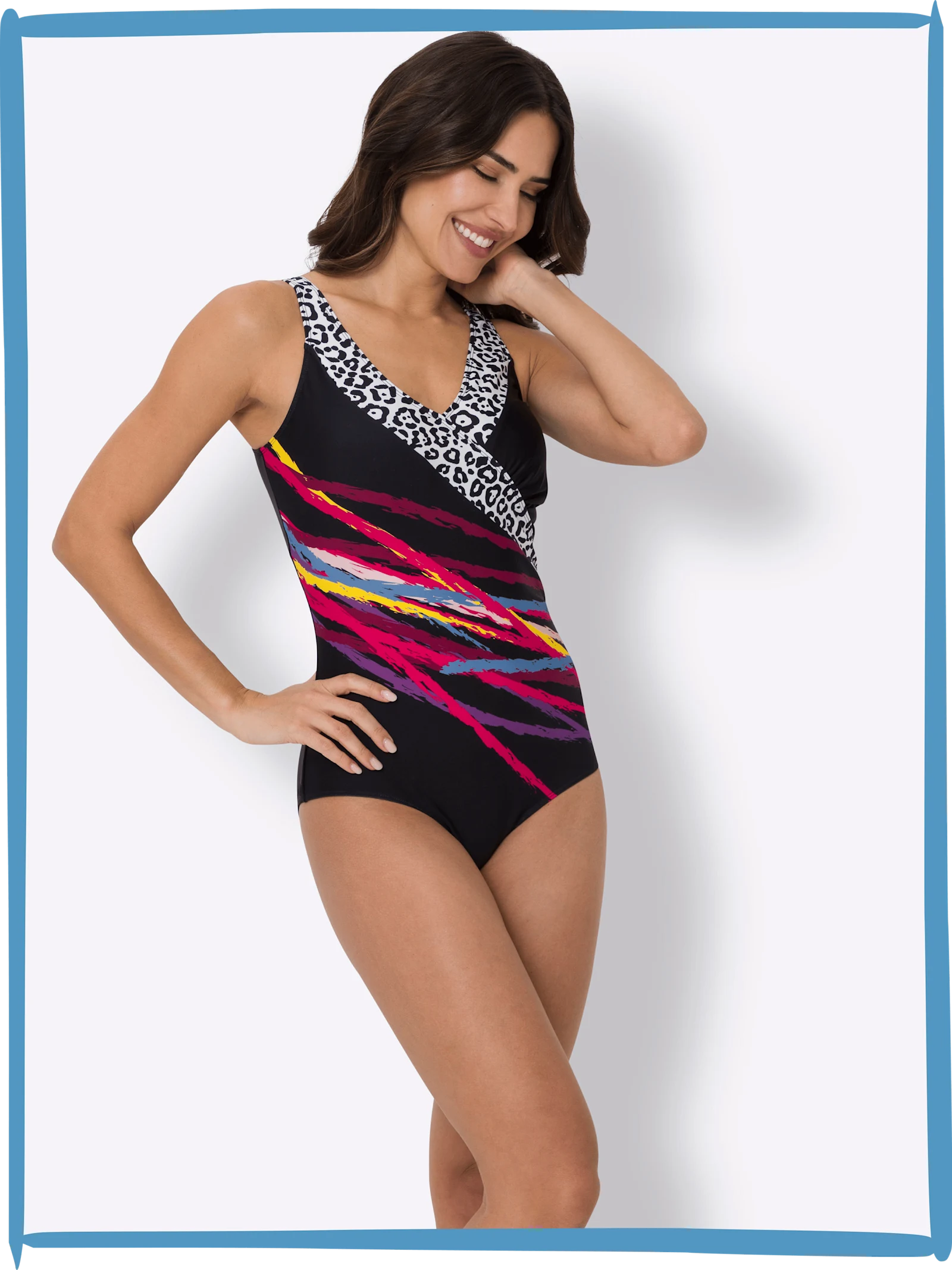 Ein Model trägt einen schwarz-bunten Badeanzug mit weißem Muster am Ausschnitt, steht vor weißem Hintergrund.