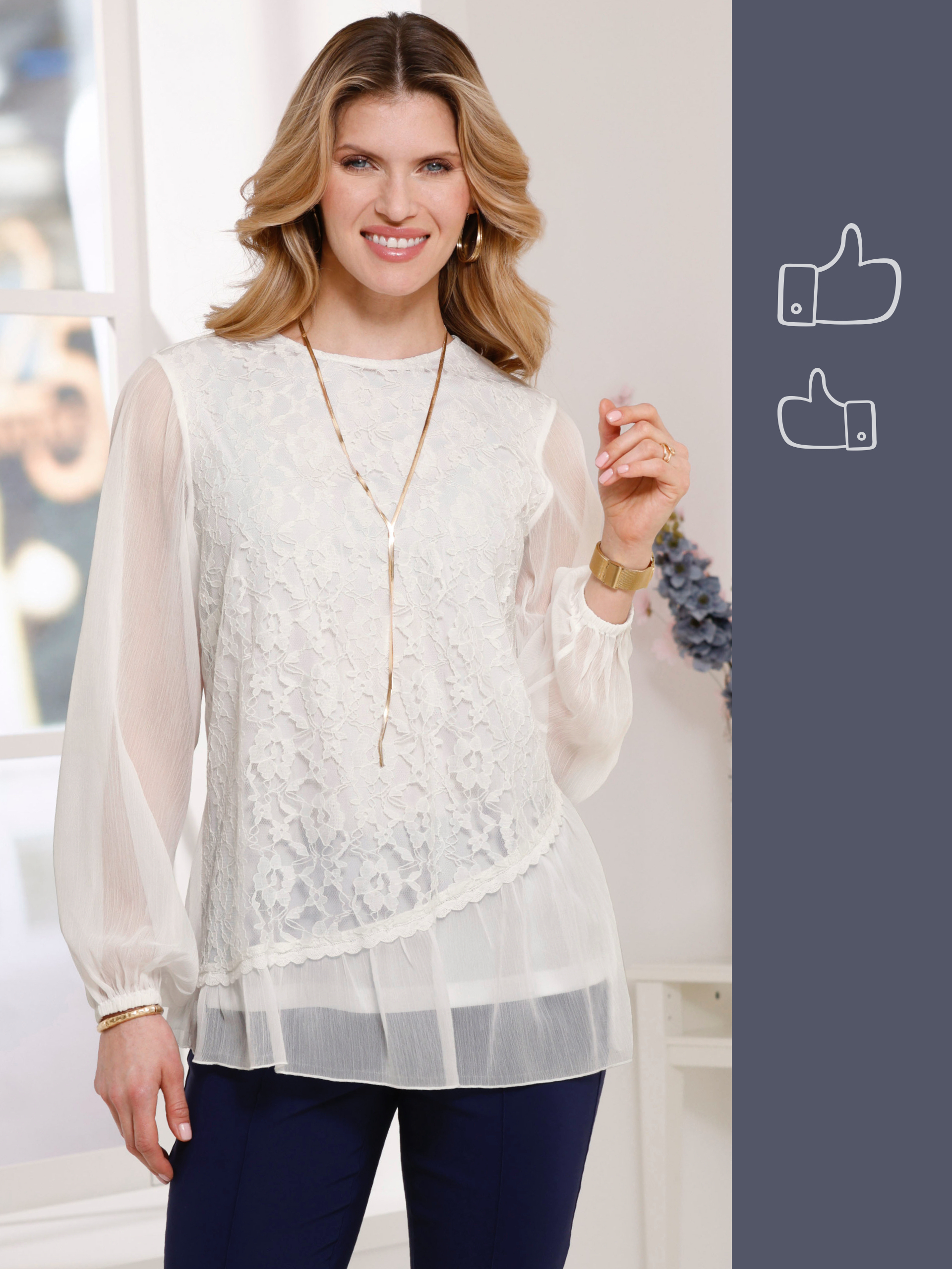 En modell med blont, vågigt hår bär en vit blus med spets, ett guldhalsband och en klocka. Hon ler vänligt.