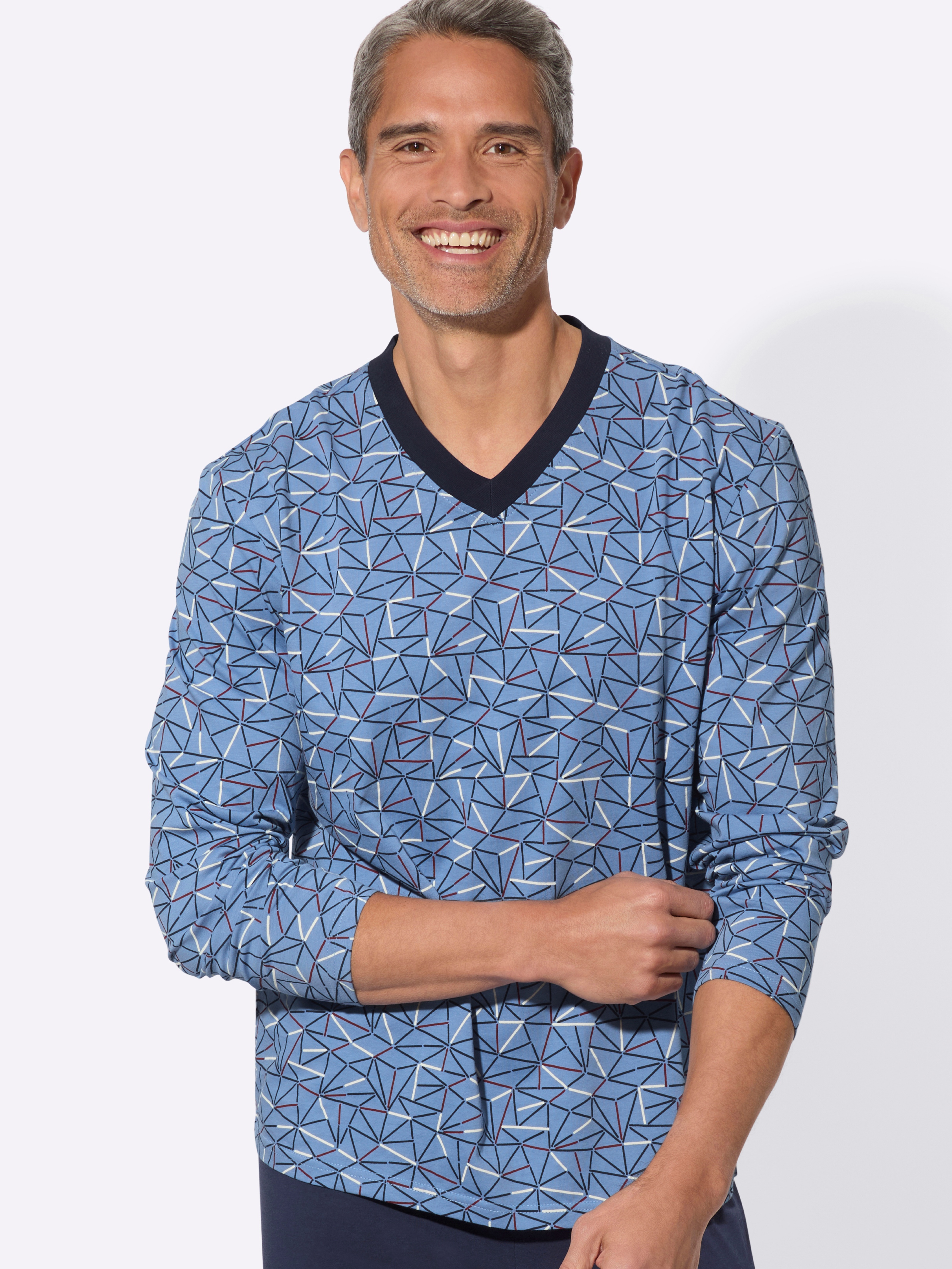 Model má oblečený modrý sveter s geometrickým vzorom a výstrihom do V.