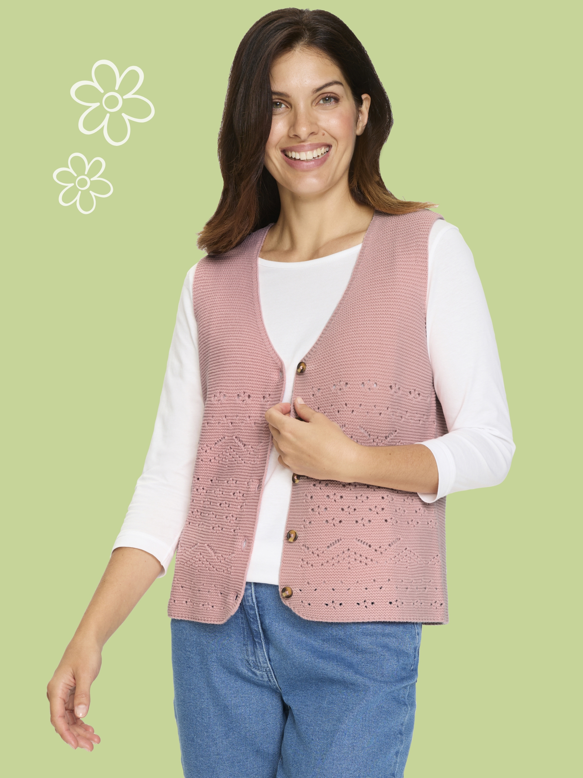 Modelka má na sebe bielu blúzku a ružovú pletenú vestu pred svetlým pozadím.