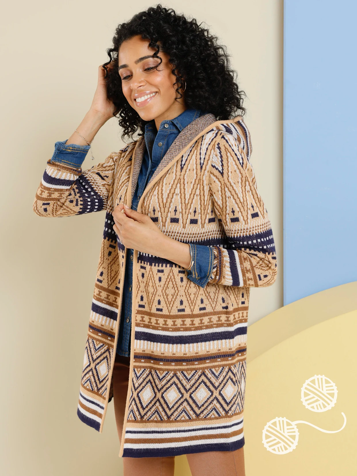 Ein Model trägt einen gemusterten Cardigan über einer blauen Bluse.