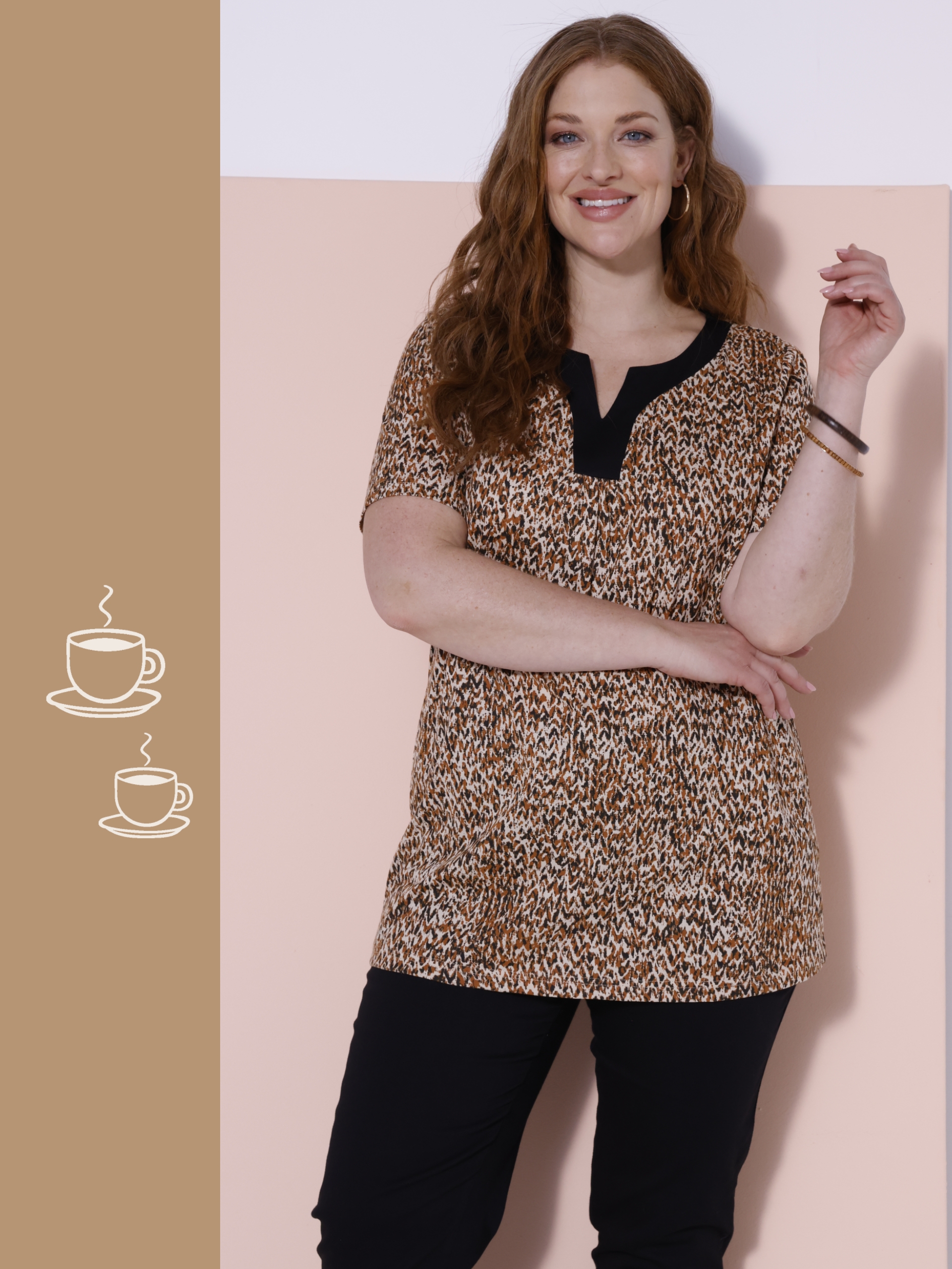 Ein Model steht vor einer zweifarbigen Wand, trägt ein kurzärmeliges, gemustertes Oberteil mit schwarzem Kragen und schwarze Hosen.