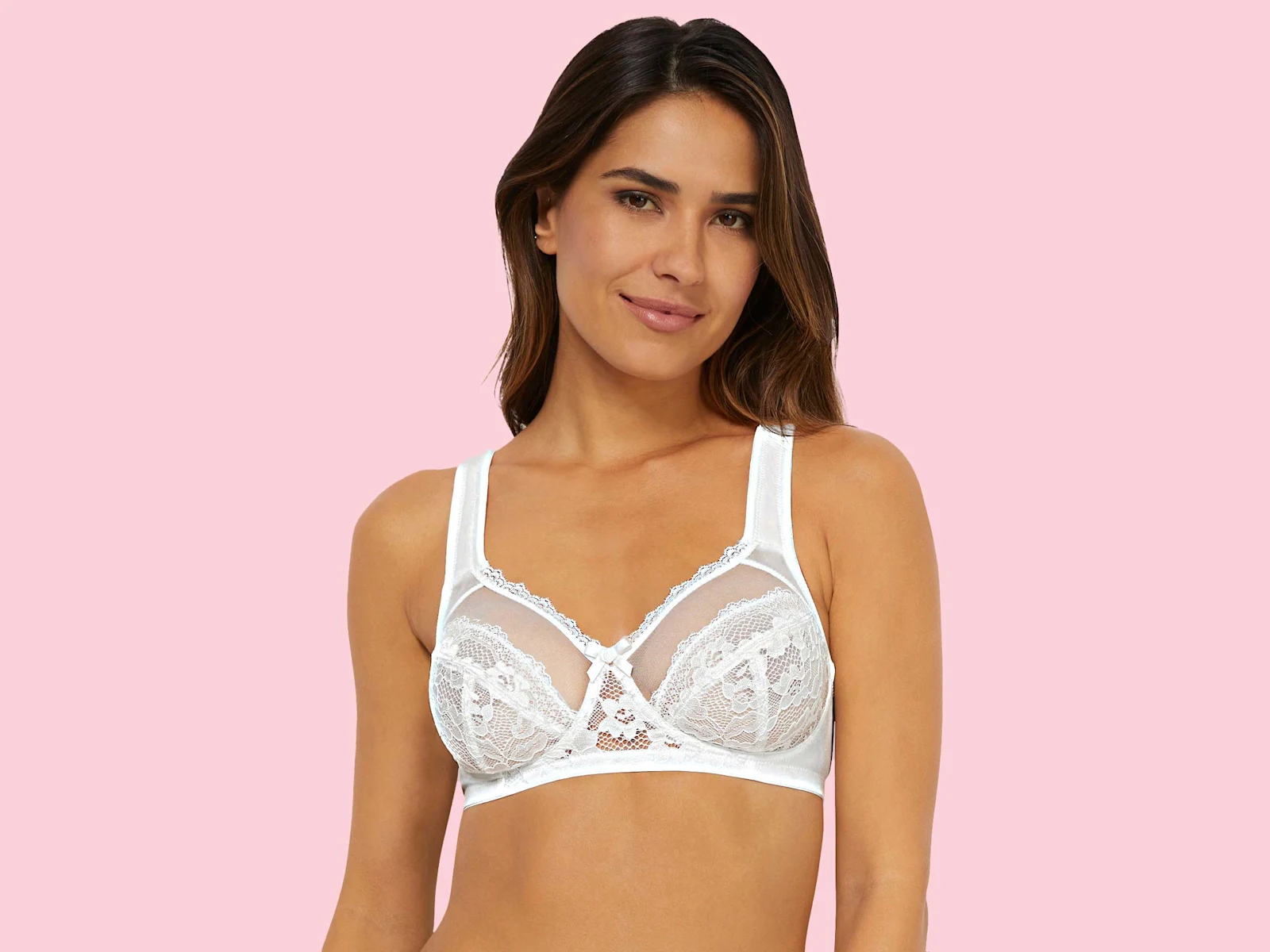 Bílá krajková podprsenka na růžovém pozadí.