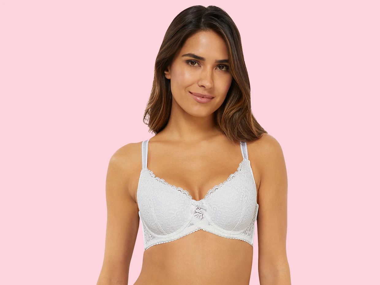 Witte kanten bh met verstelbare bandjes en lichtroze achtergrond.