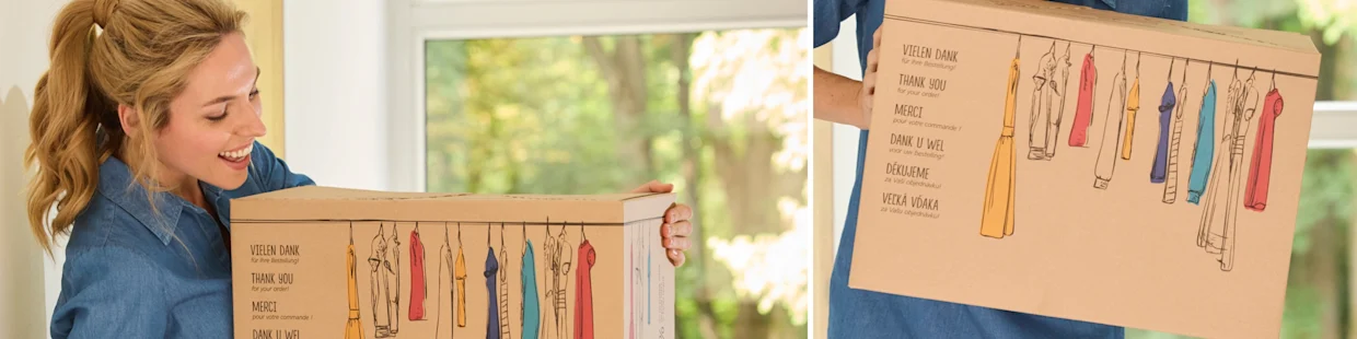 Karton mit bunter Kleidungsgrafik und mehrsprachigem Dankesgruß, gehalten von einer Person in blauem Hemd vor einem Fenster mit grünem Ausblick. Karton mit bunter Kleidungsgrafik und mehrsprachigem Dankesgruß, gehalten von einer Person in blauem Hemd vor einem Fenster mit grünem Ausblick.