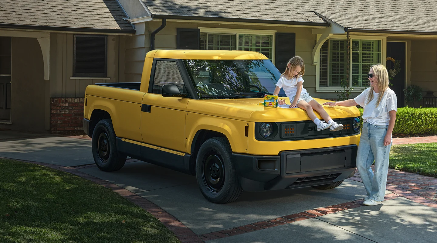 Child sitting on hood of yellow Slate in driveway
